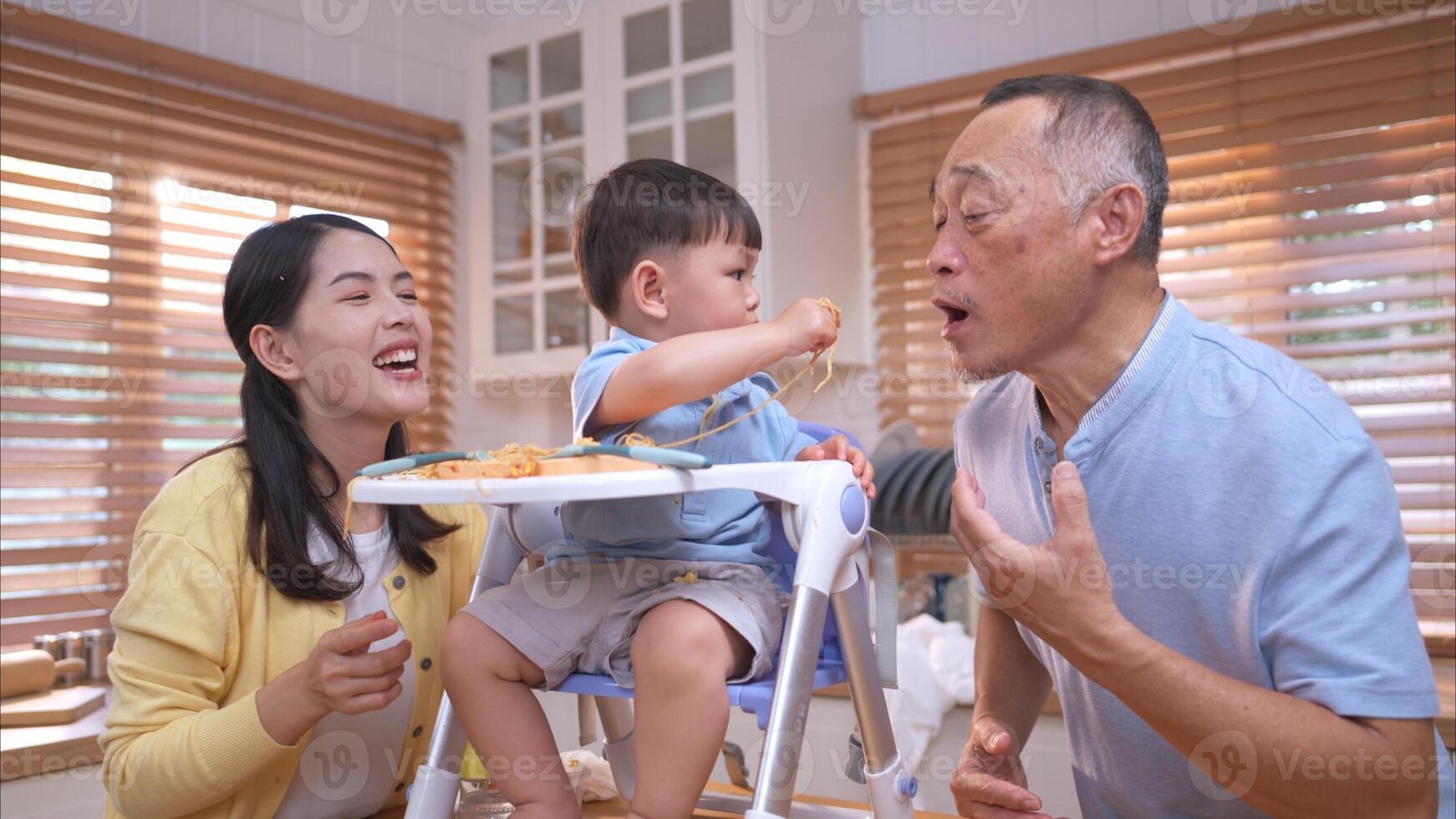 Happy Asian parents enjoying mealtime with their toddler in the kitchen,210 photo