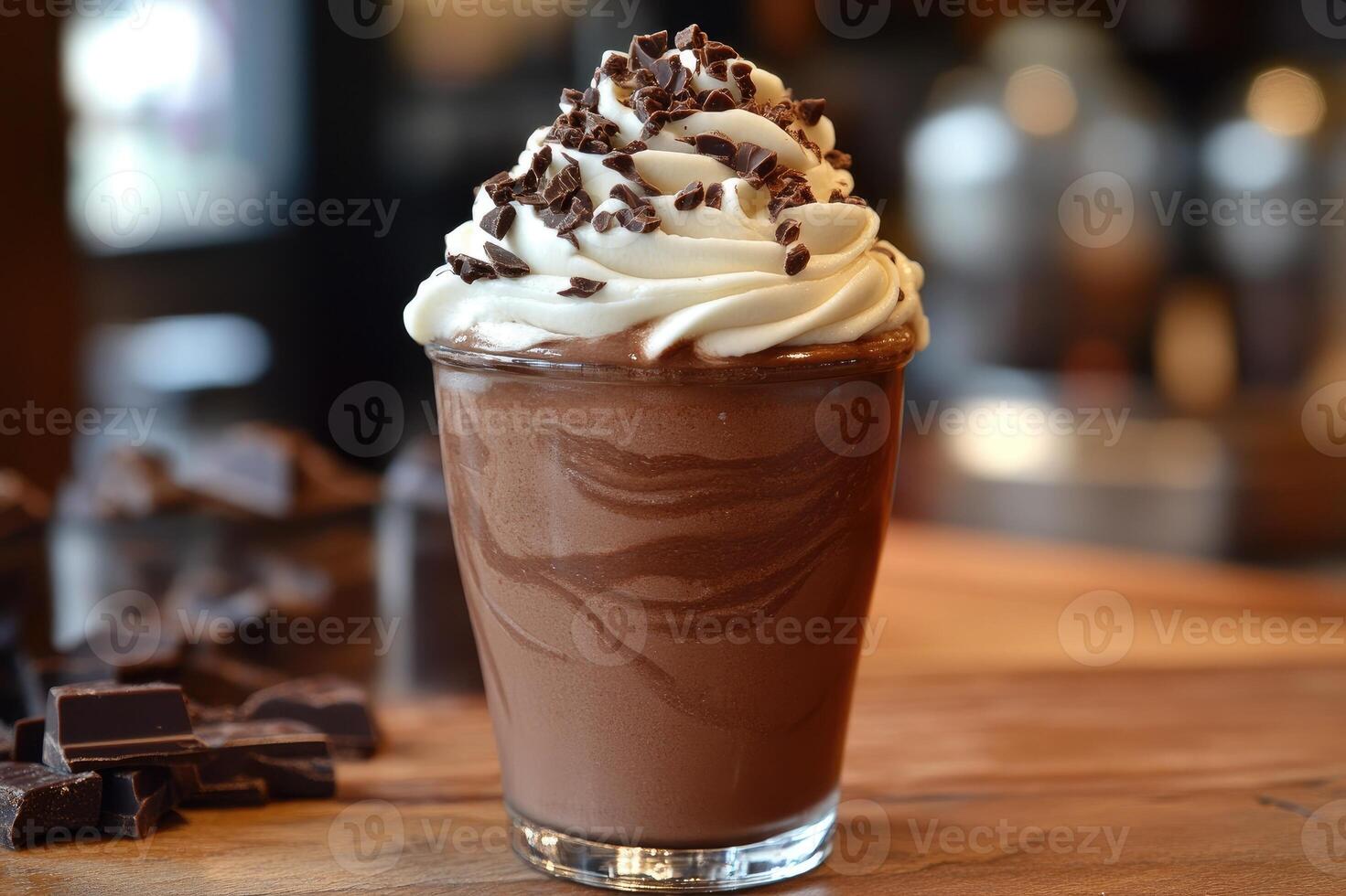 Delicious chocolate milkshake topped with whipped cream and chocolate shavings is waiting on a wooden table photo