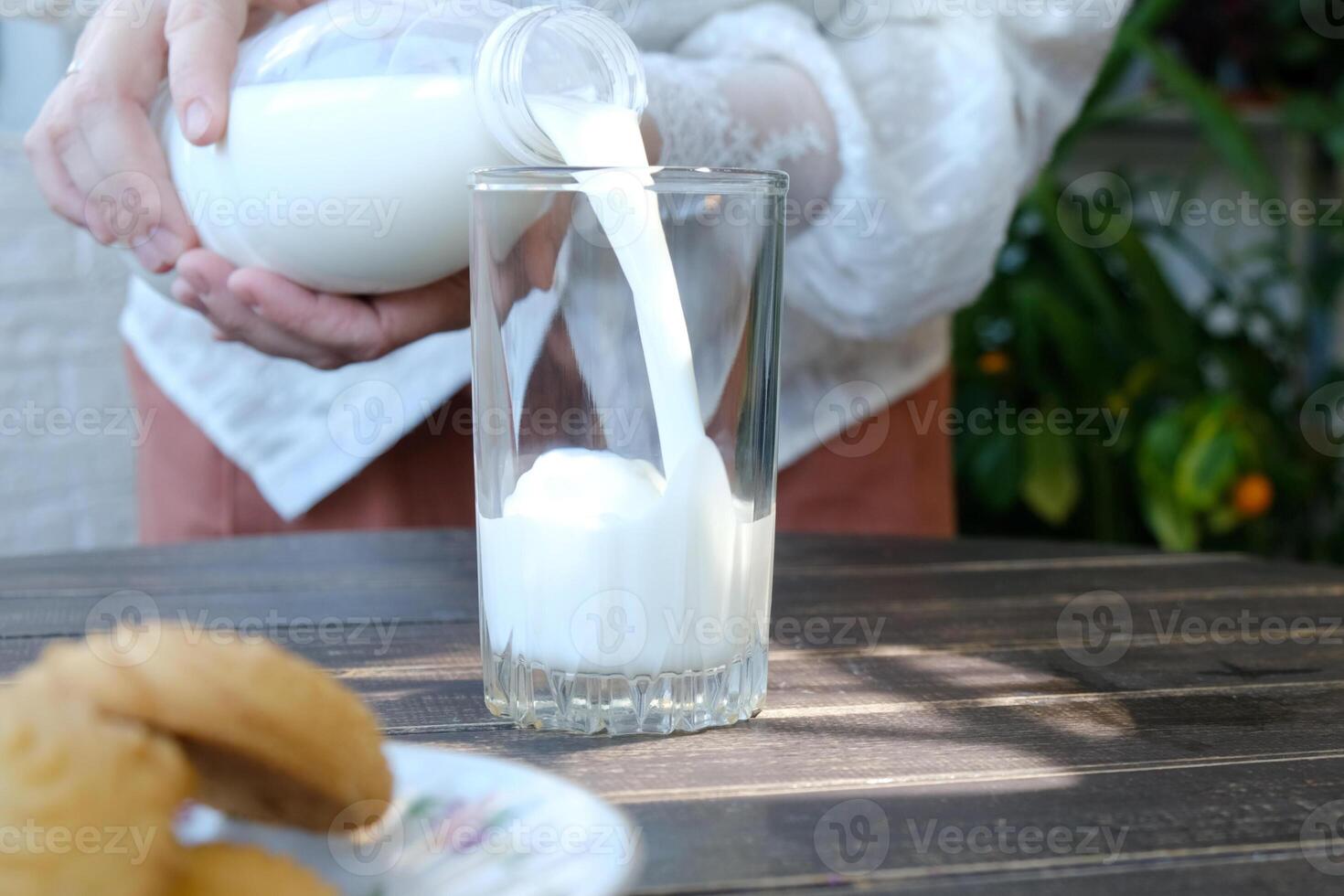 Pouring milk into transparent glass. Person drinking milk. photo