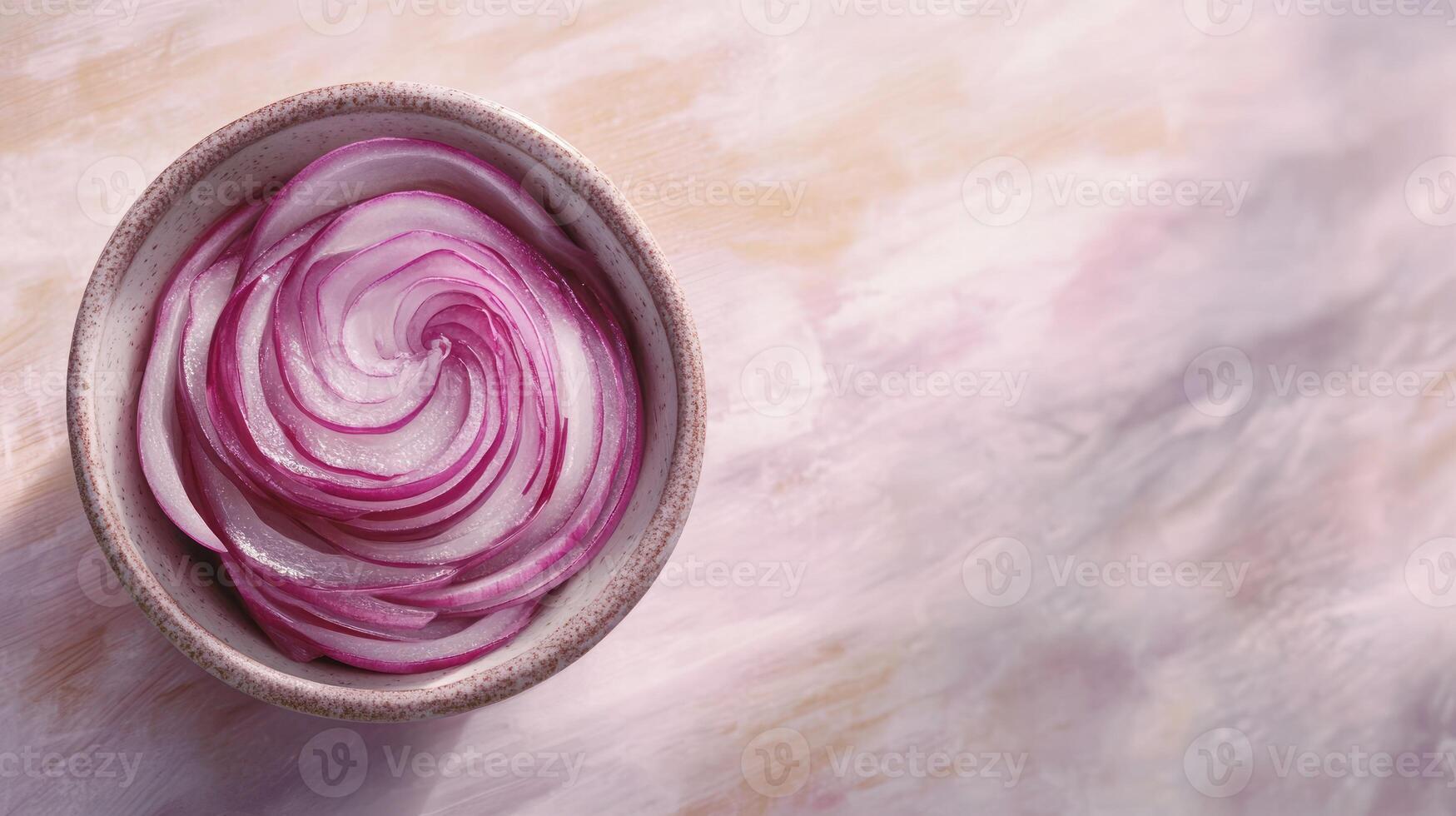 Thinly sliced red onion rings arranged in a spiral pattern in a light-colored bowl, resting on a pale, textured surface photo