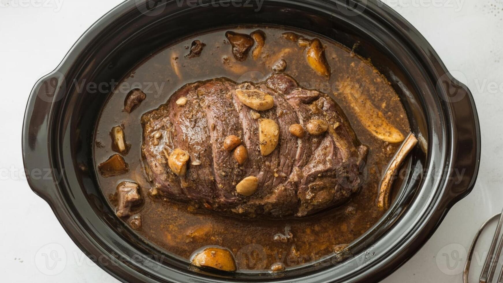 Close up of a pot roast with mushrooms and garlic in a black slow cooker pot photo