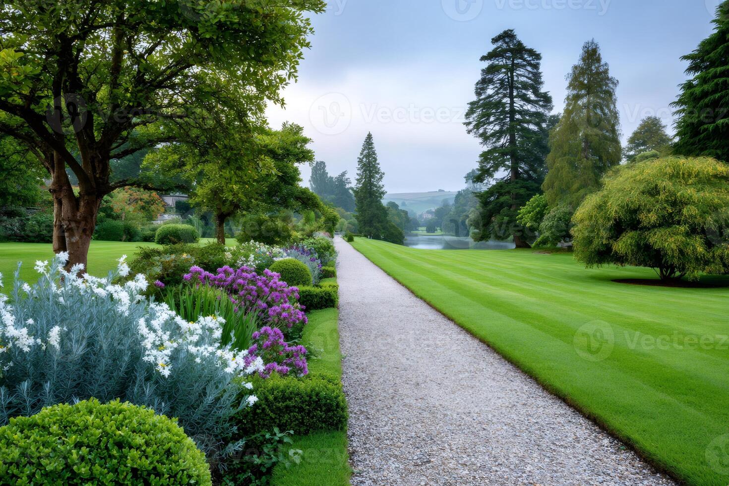Gravel path winding through a lush garden alongside a tranquil lake photo