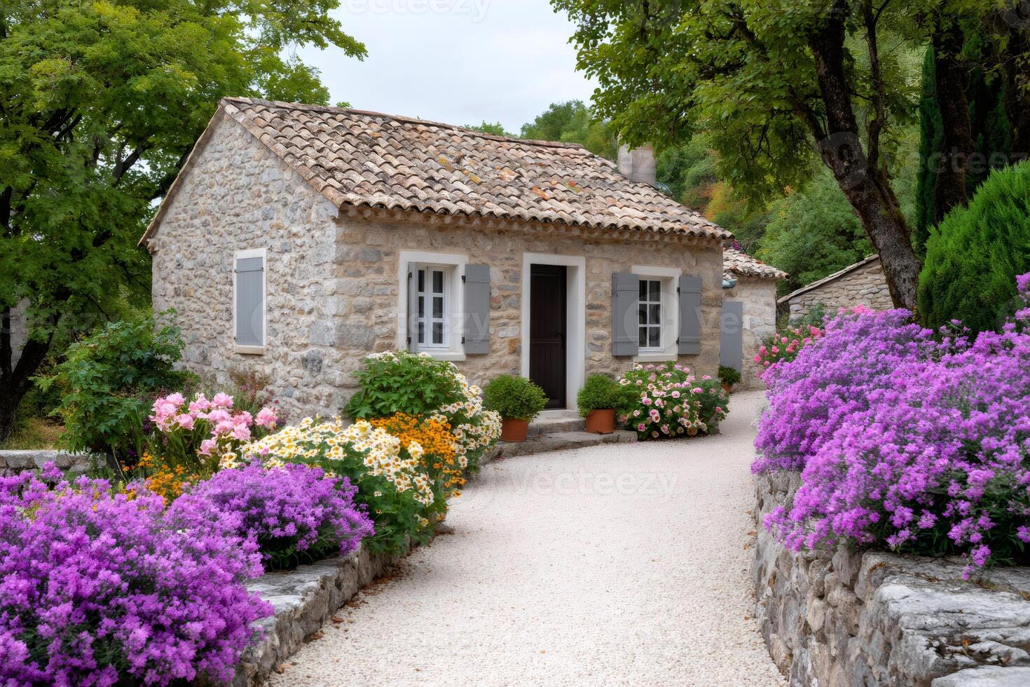 Charming stone house with blooming garden and gravel pathway photo