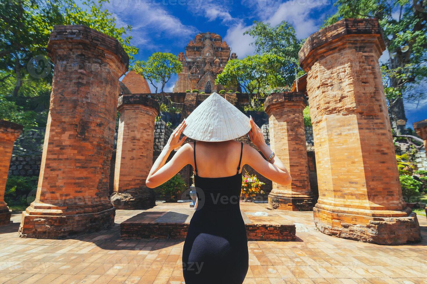 A female tourist stands with her back against the background View of Po Nagar Cham towers complex photo