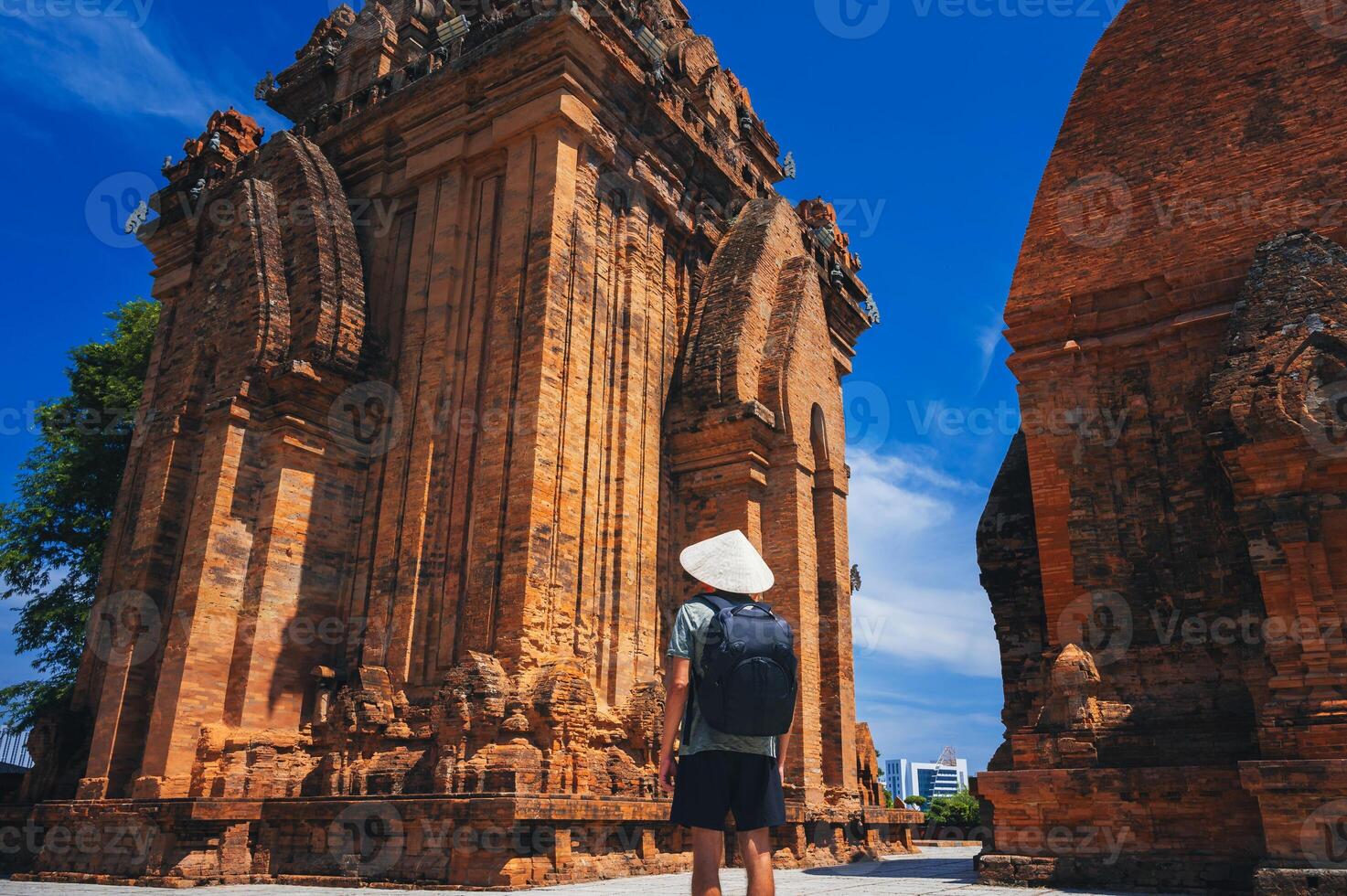 A tourist in a Vietnamese hat stands with his back against the background of the Ponagar Tower photo