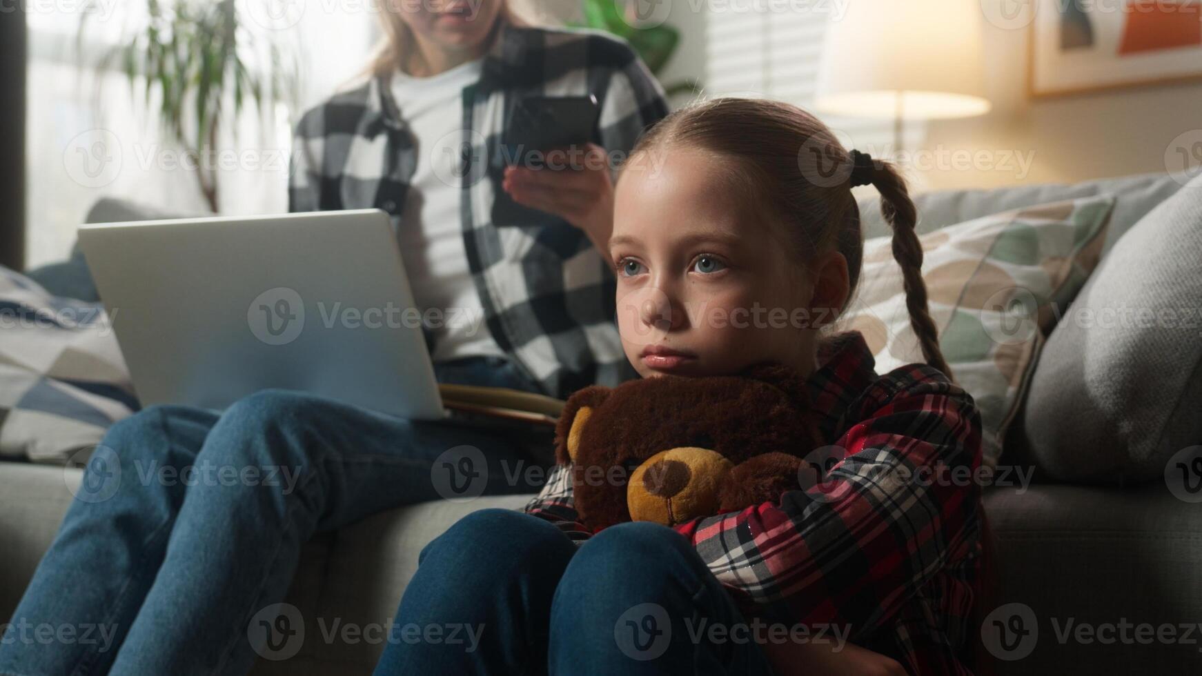 Caucasian family upset lonely kid girl suffering busy mother woman using laptop working from home ignoring child daughter holding Teddy Bear parenting ignore lack of attention childcare trouble stress photo