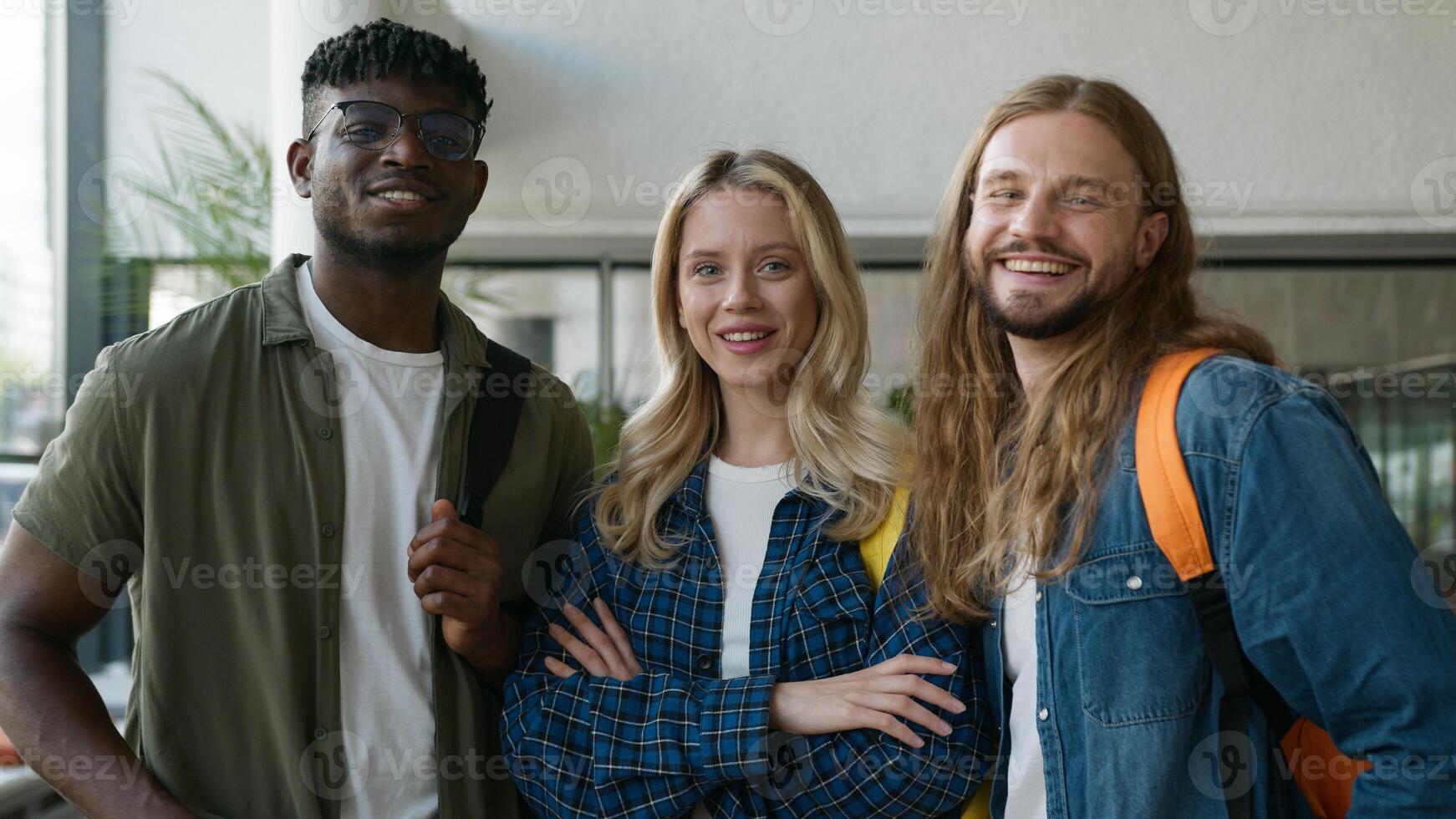 Closeup three multiracial friends diversity students smiling looking at camera Caucasian woman girl female with African American man guy male posing in university corridor hall together smile positive photo