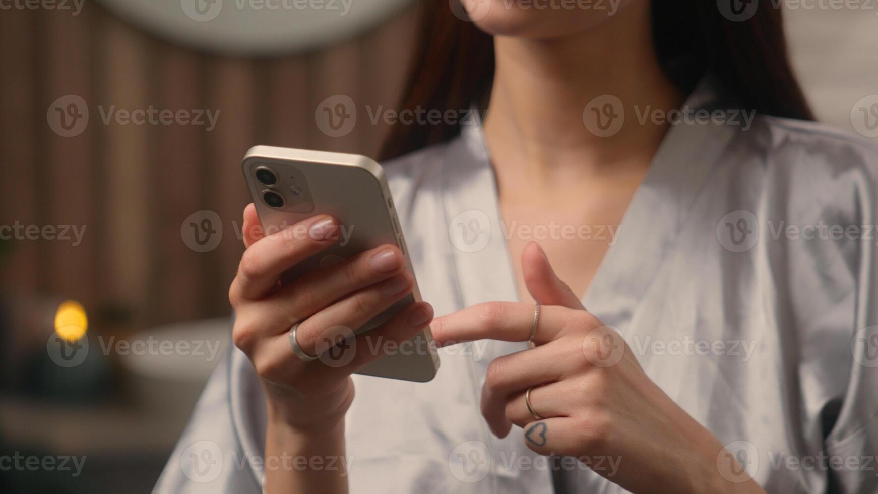 Close up cropped view at home bathroom woman female hands lady girl indoor using mobile phone online smartphone internet web net cellphone social media app browsing chatting shopping buying cosmetic photo