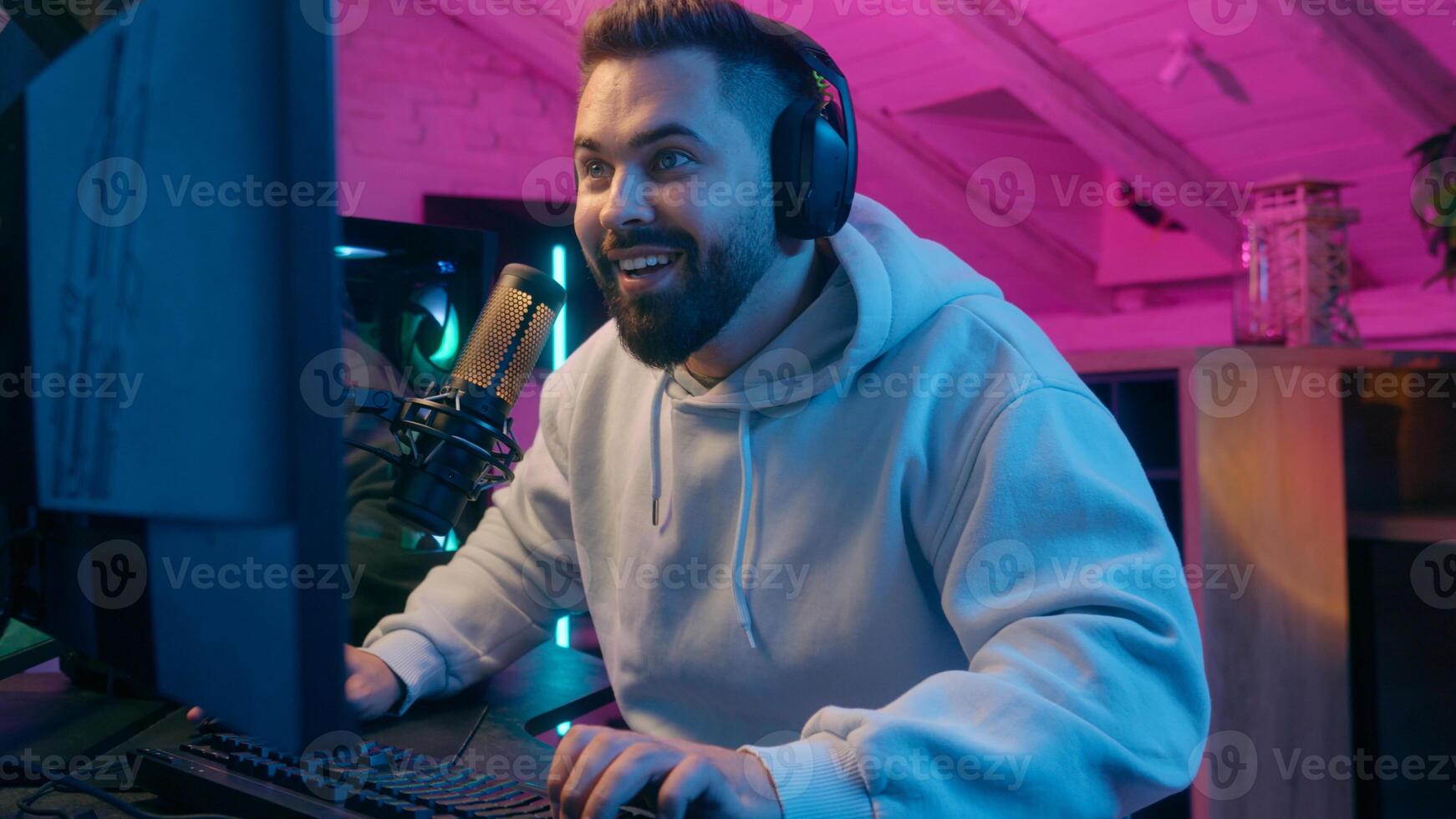 Excited winner champion Caucasian guy male gamer streamer man winning luck achievement victory internet win talking microphone play online game addict in headphones gaming streaming in neon dark room photo