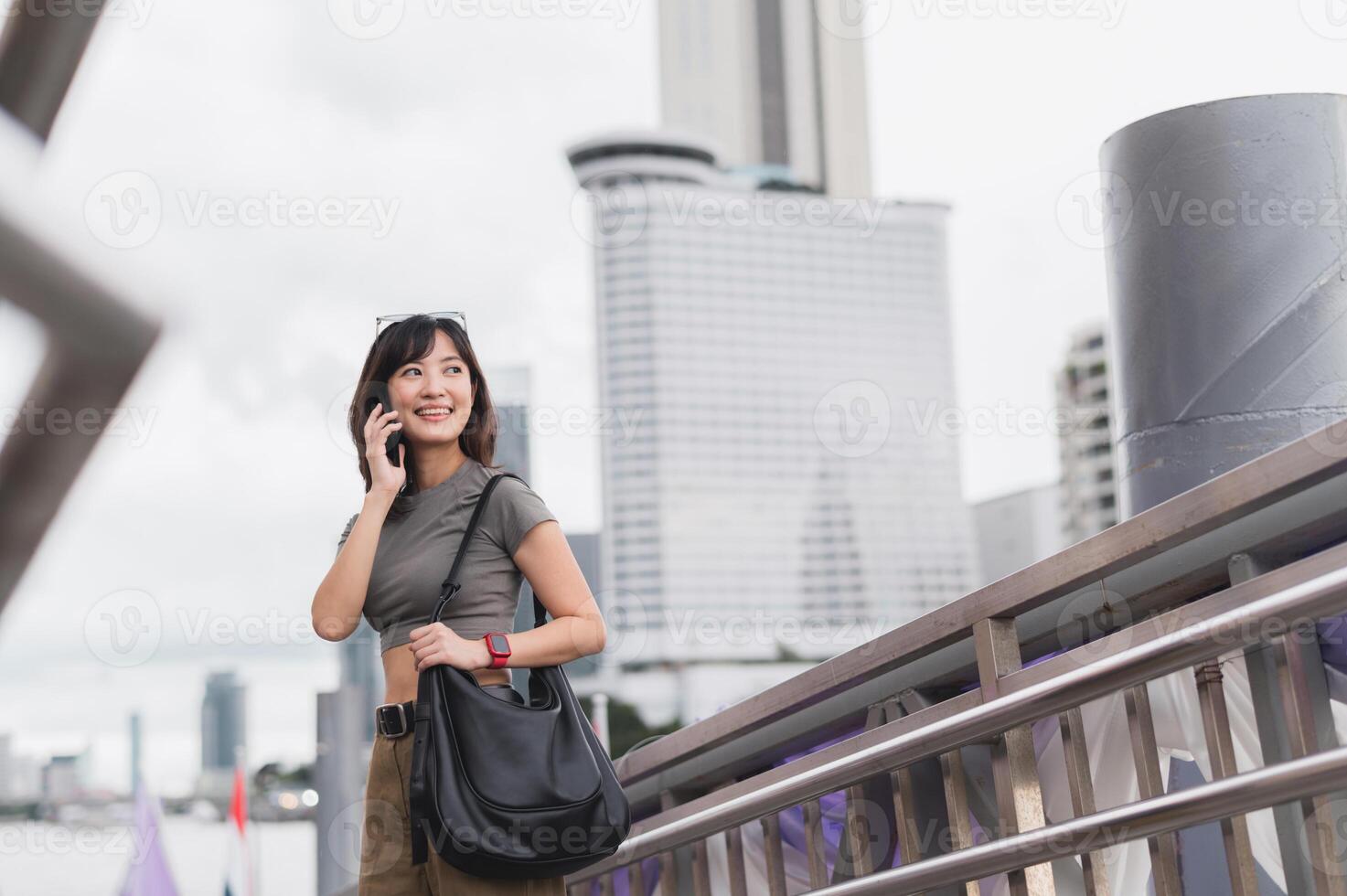 Solo southeast asian woman teenager blogger world travel tourism Bangkok Thailand express joy to friend smartphone. Wait for Chao Phraya river boat for local cultural experience. Asia explorer photo