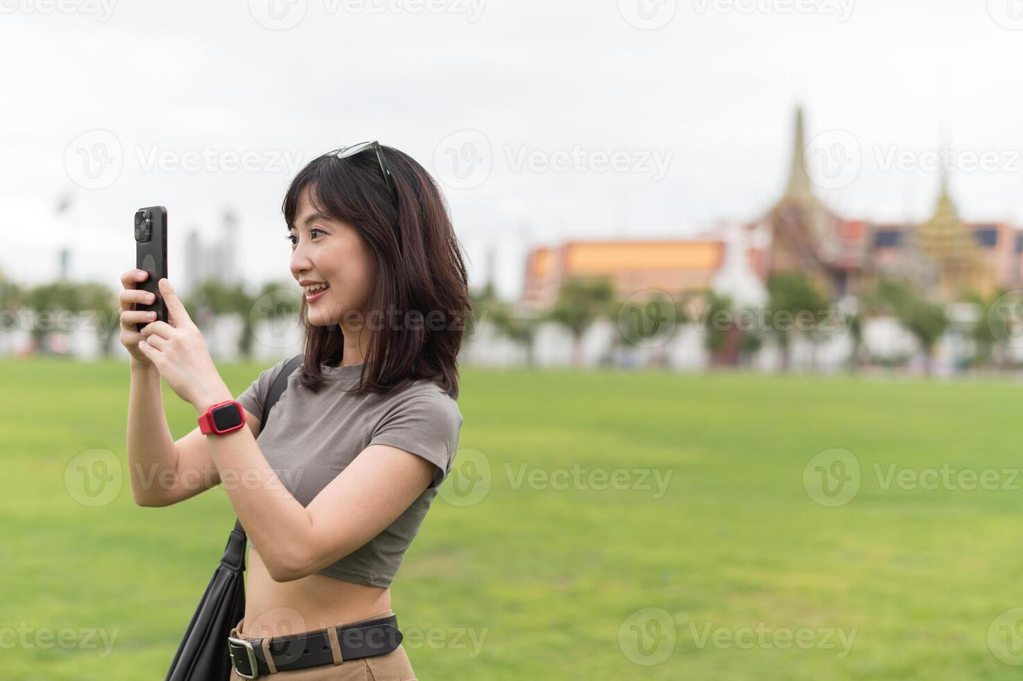 Happy southeast asian woman teenager blogger on solo world travel take photo with smartphone for local cultural experience. cheerful explorer enjoying asia tourism concept in Bangkok Thailand