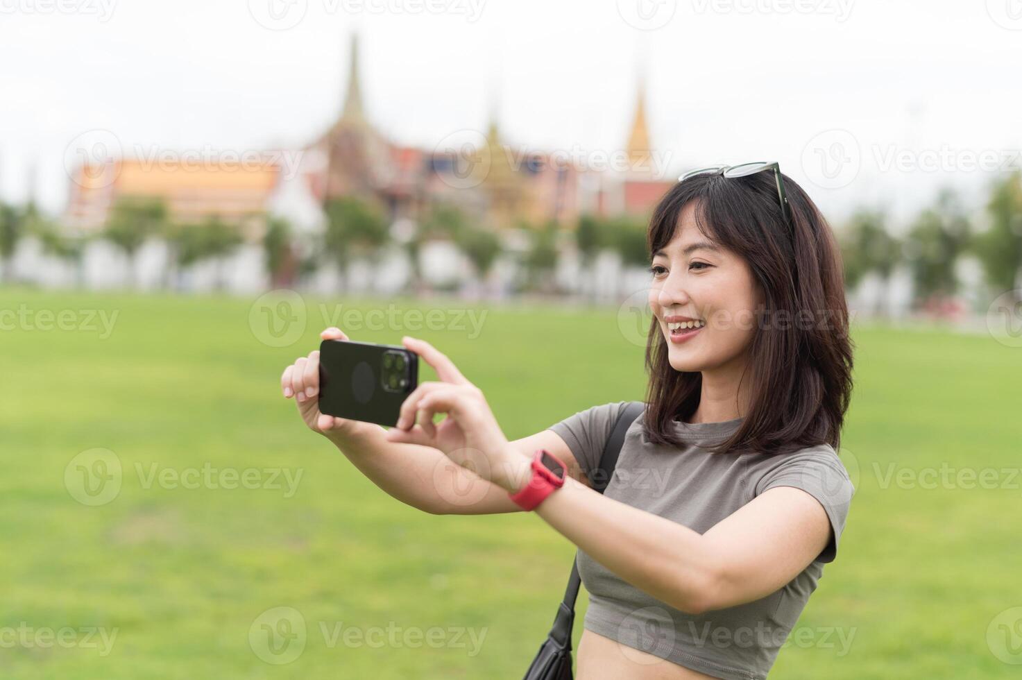 Southeast asian woman teenager blogger solo world travel explorer take photo with smartphone. happy local cultural experience in Bangkok Thailand. Asia tourism concept