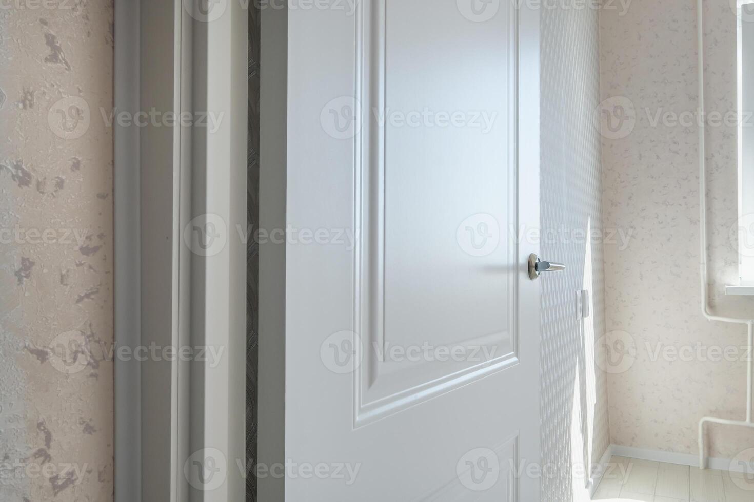A white door is open in a room with a window photo