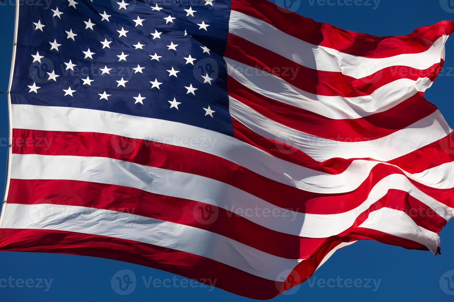 USA American Flag Waving In The Wind Against Deep Blue Sky. photo