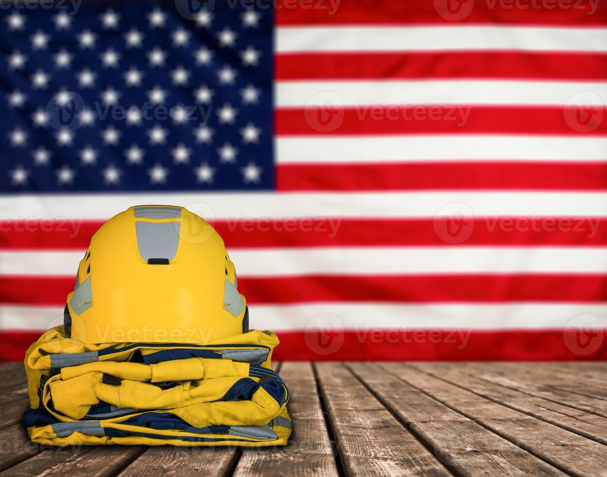Protective yellow helmet and uniform placed on wooden surface against the background of the United States flag. Stock photo. photo