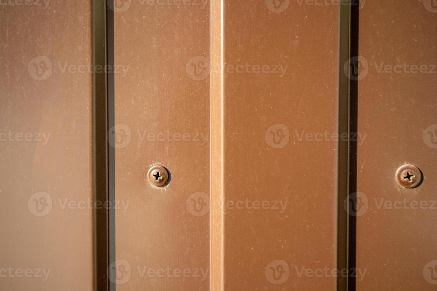 Brown industrial background self-tapping screw in corrugated sheet close-up photo