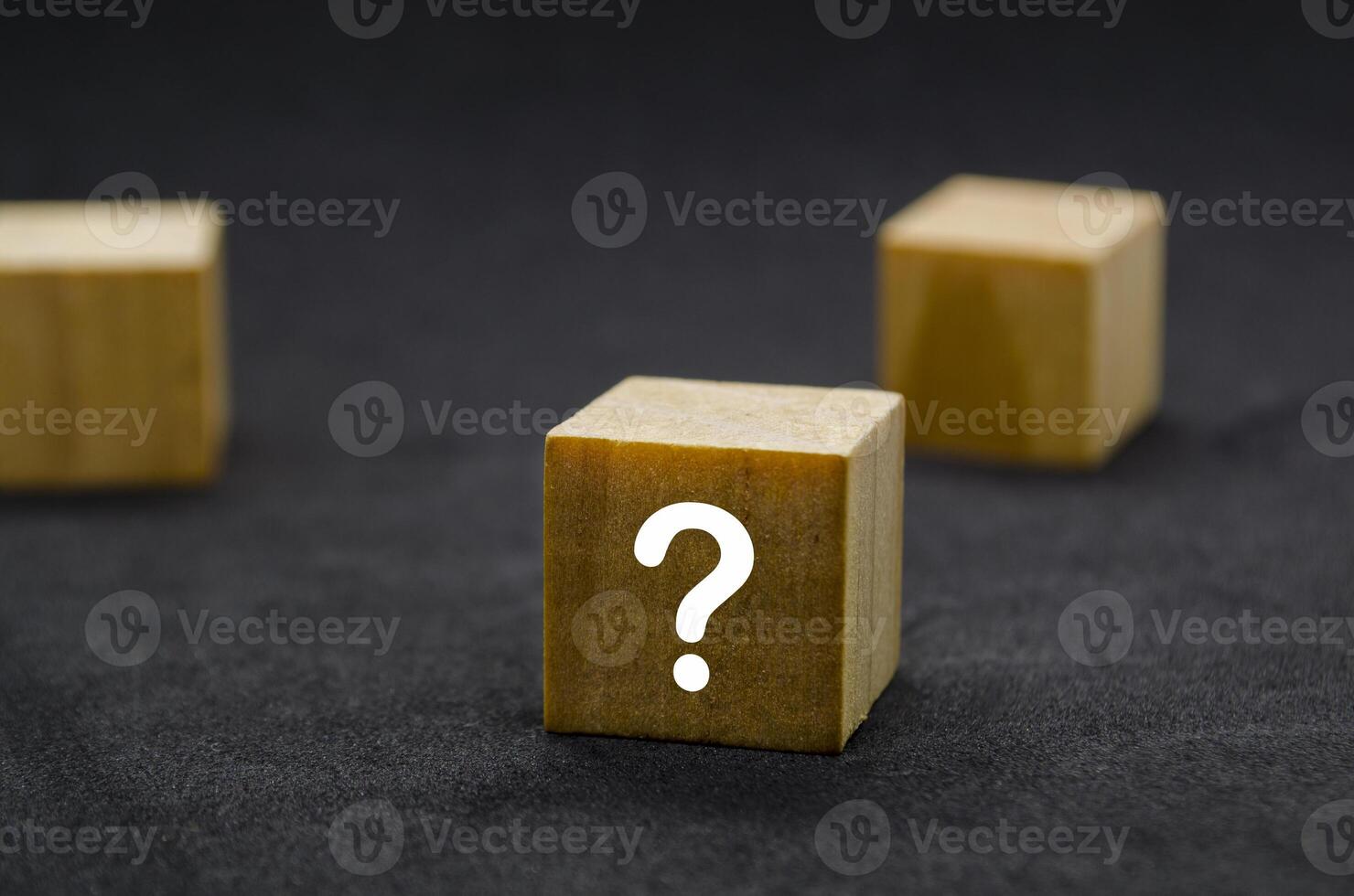 Three wooden cubes with question marks aligned in a row photo