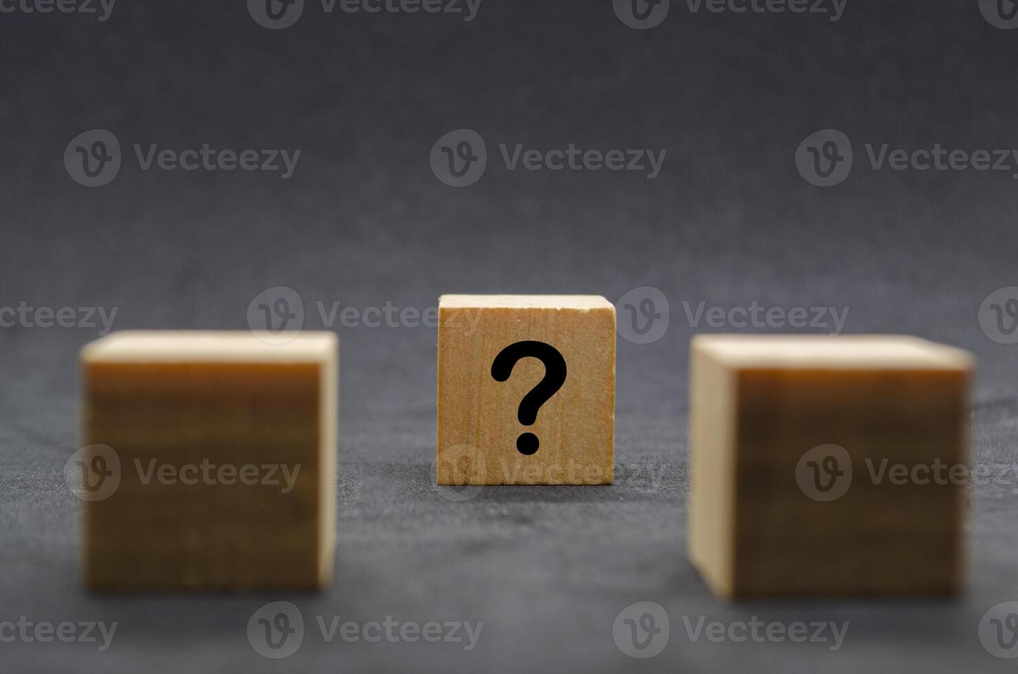 Two dark wooden cubes with question marks on a black background photo