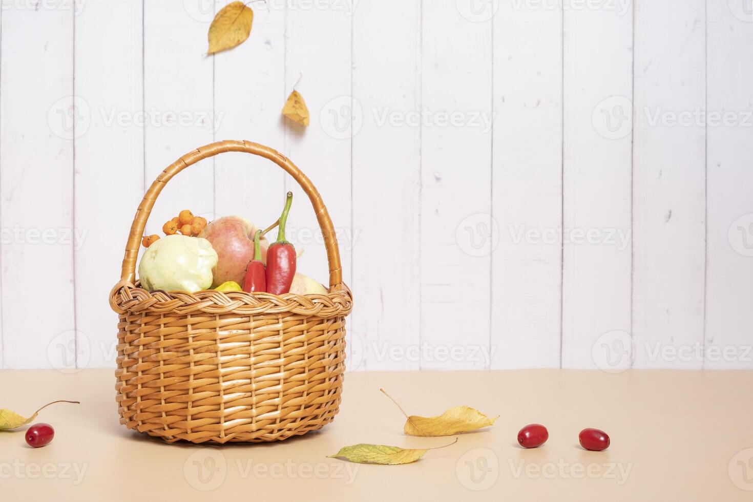 Autumn harvest basket with apples, zucchini and peppers on a wooden background. photo