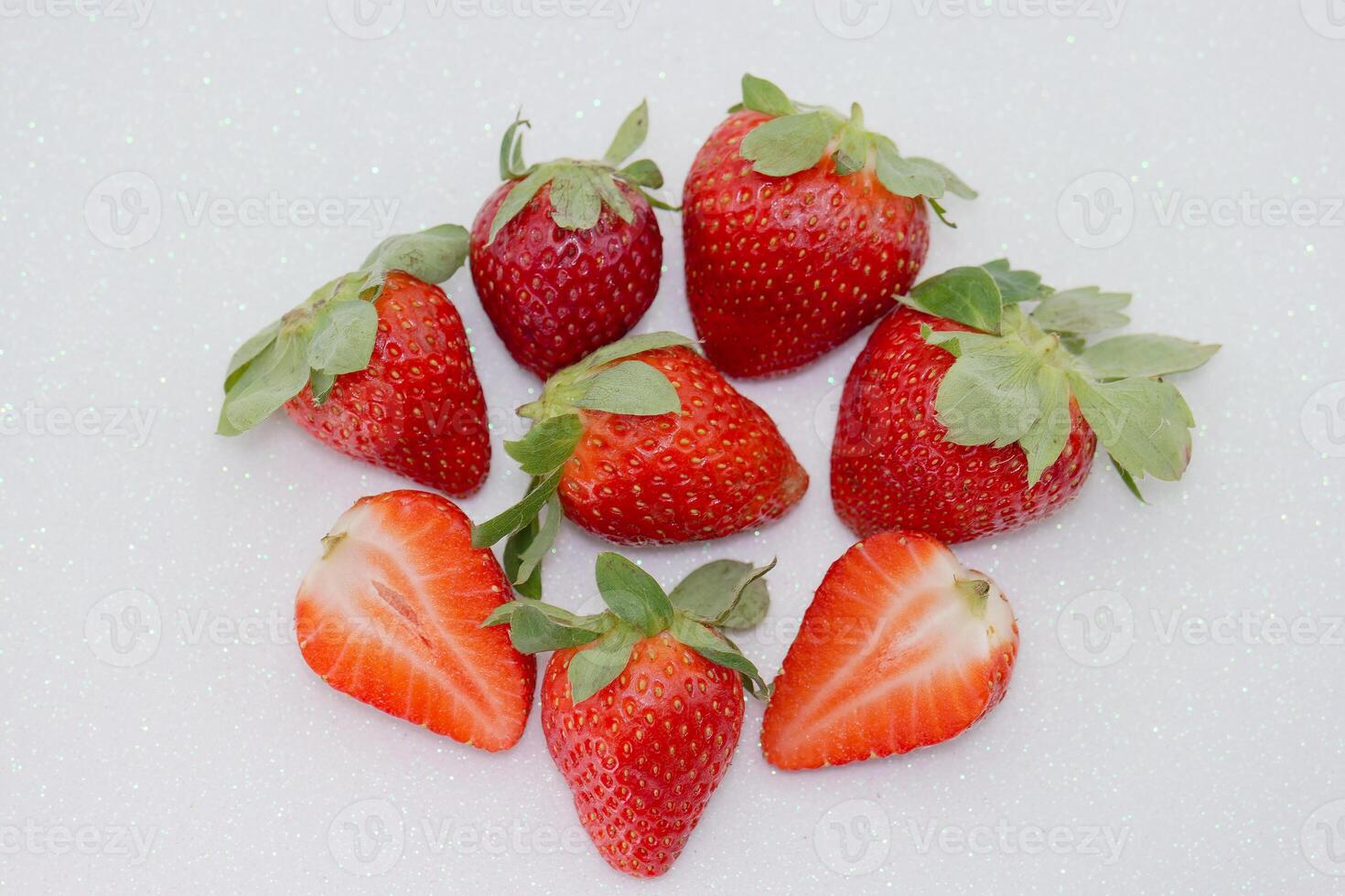Freshly harvested strawberries arranged in a circular pattern on a light background showcasing bright red color and greenery photo