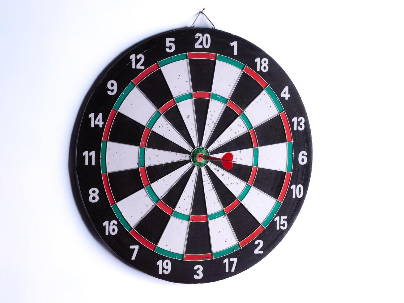 Red dart hitting bullseye on dartboard isolated on white background. Perfect target accuracy, success, focus, business strategy, goal achievement, competition and leadership concept. photo