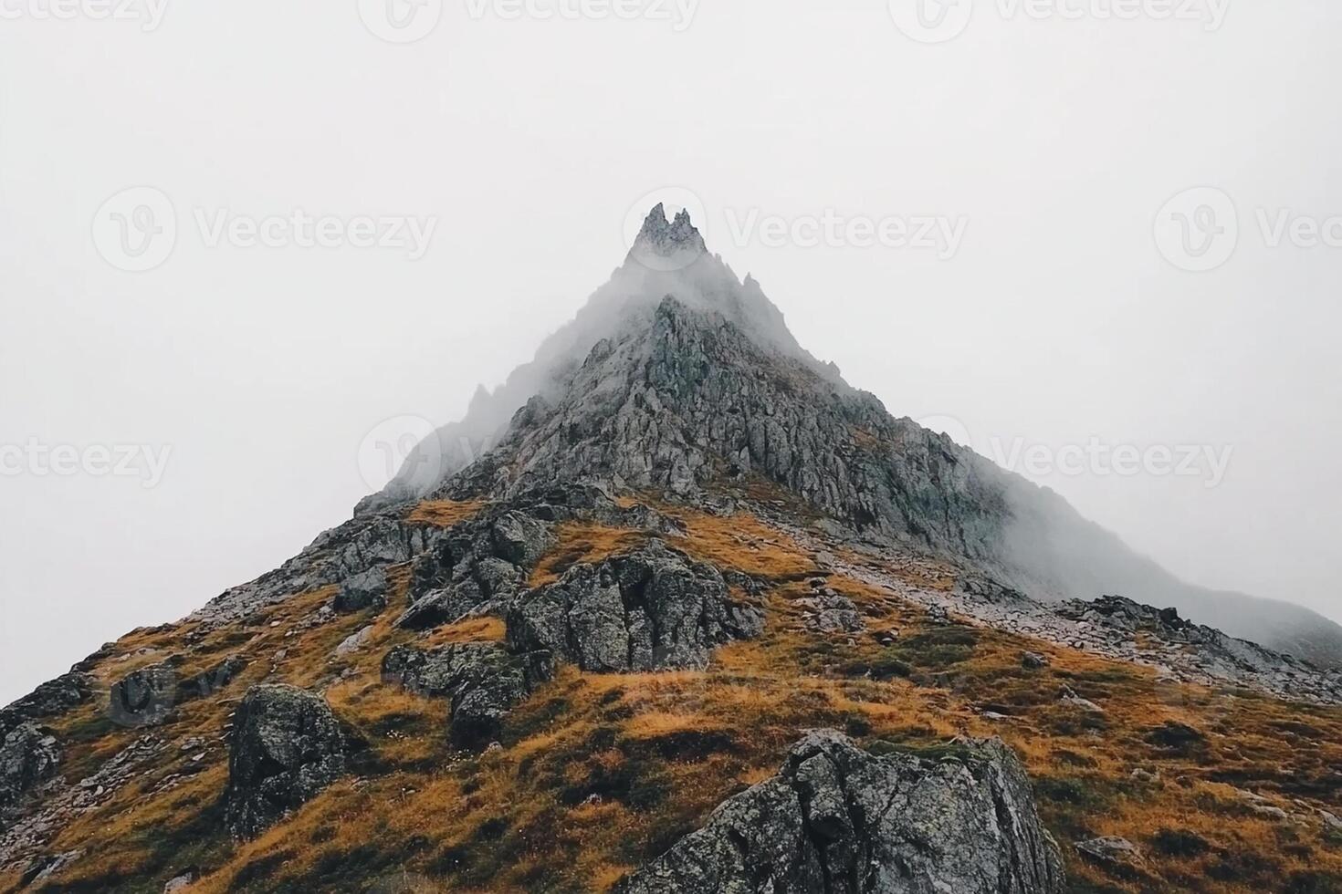 A mountain with a foggy sky and grass photo