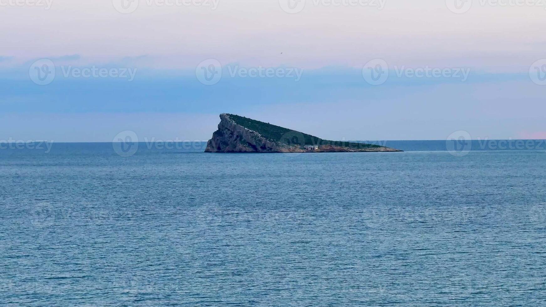 A stunning view of a distinctive island surrounded by calm, tranquil ocean waters during the beautiful dusk hour photo
