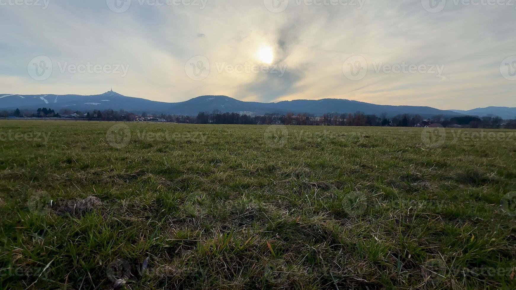 A stunningly peaceful landscape featuring majestic mountains, an open grassy field, and a tranquil dusk sky photo