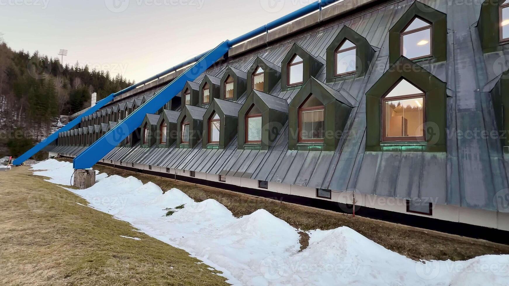 This innovative building showcases striking geometric windows set against a picturesque snowy backdrop photo