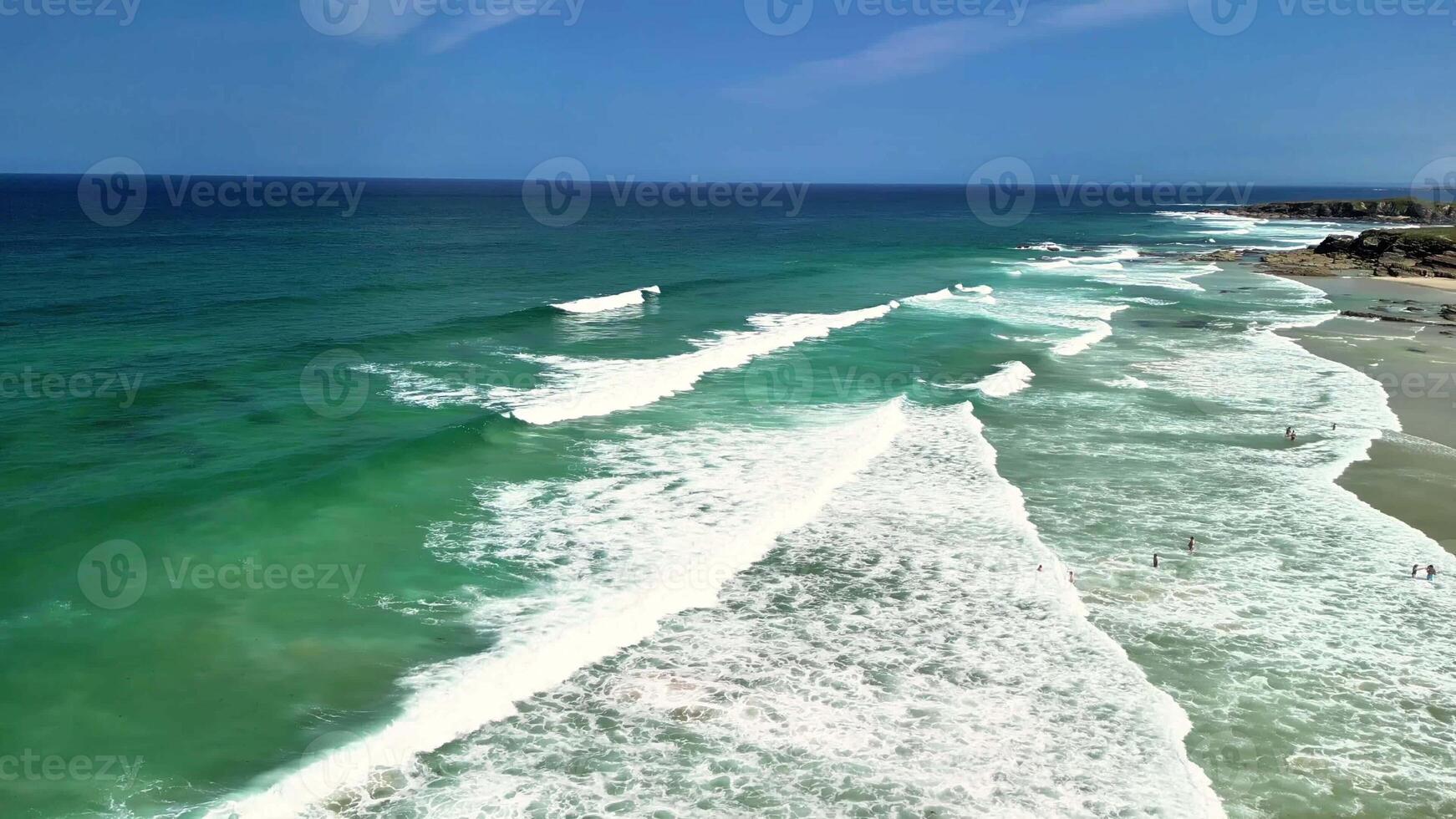 Enjoy a breathtaking aerial view of the tranquil ocean waves and the vibrant turquoise waters below a clear blue sky photo