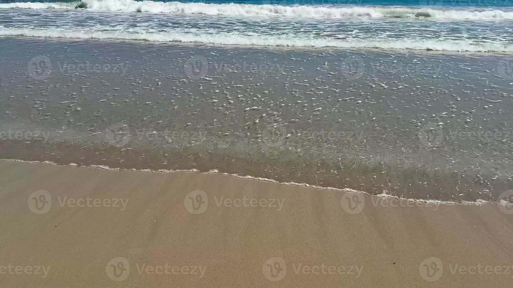 Experience the serene beauty of gentle ocean waves lapping onto a sandy beach beneath vast, clear blue skies photo