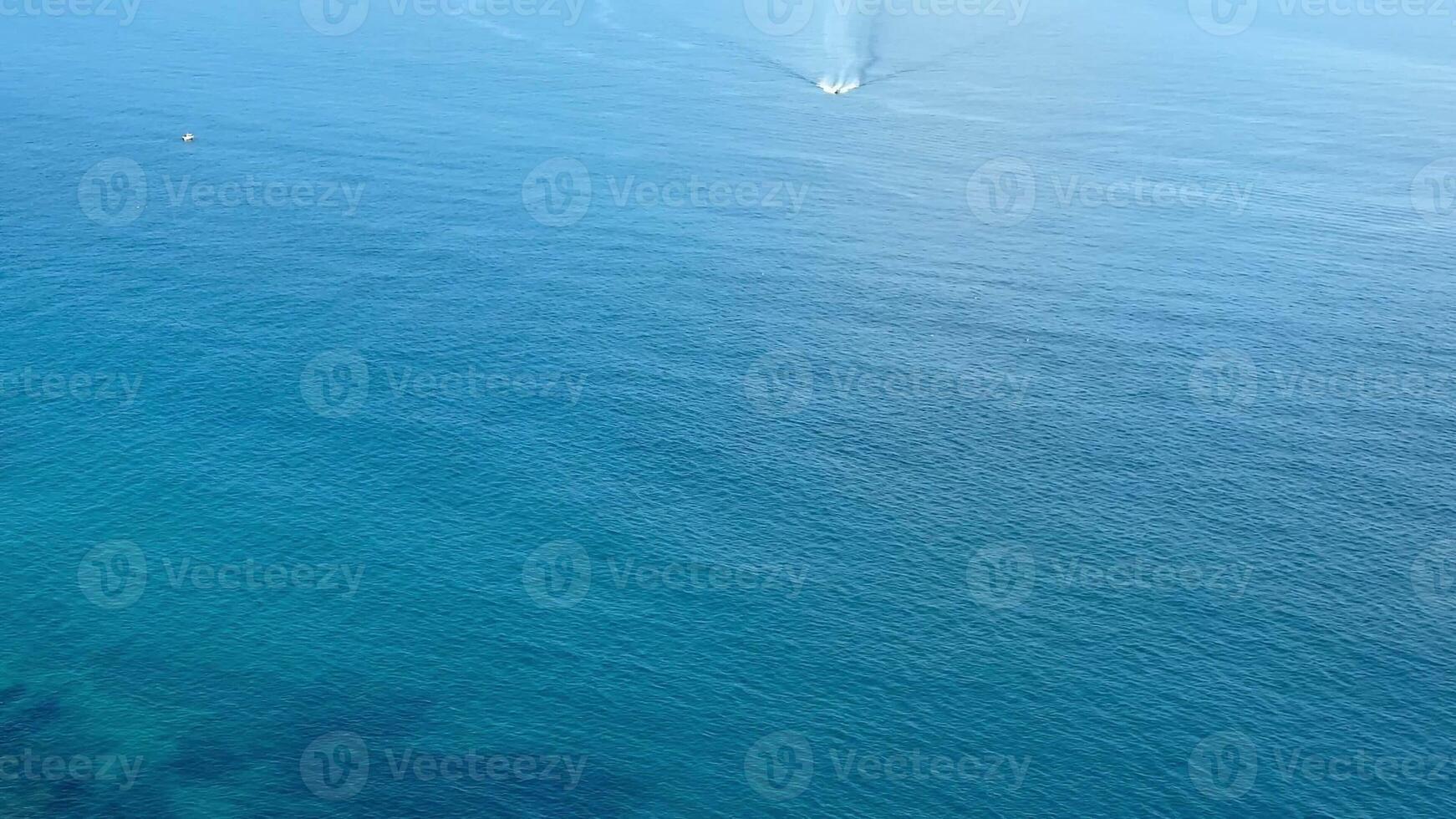 This stunning aerial photo captures serene ocean waves and a boat near a beautiful coastal landscape