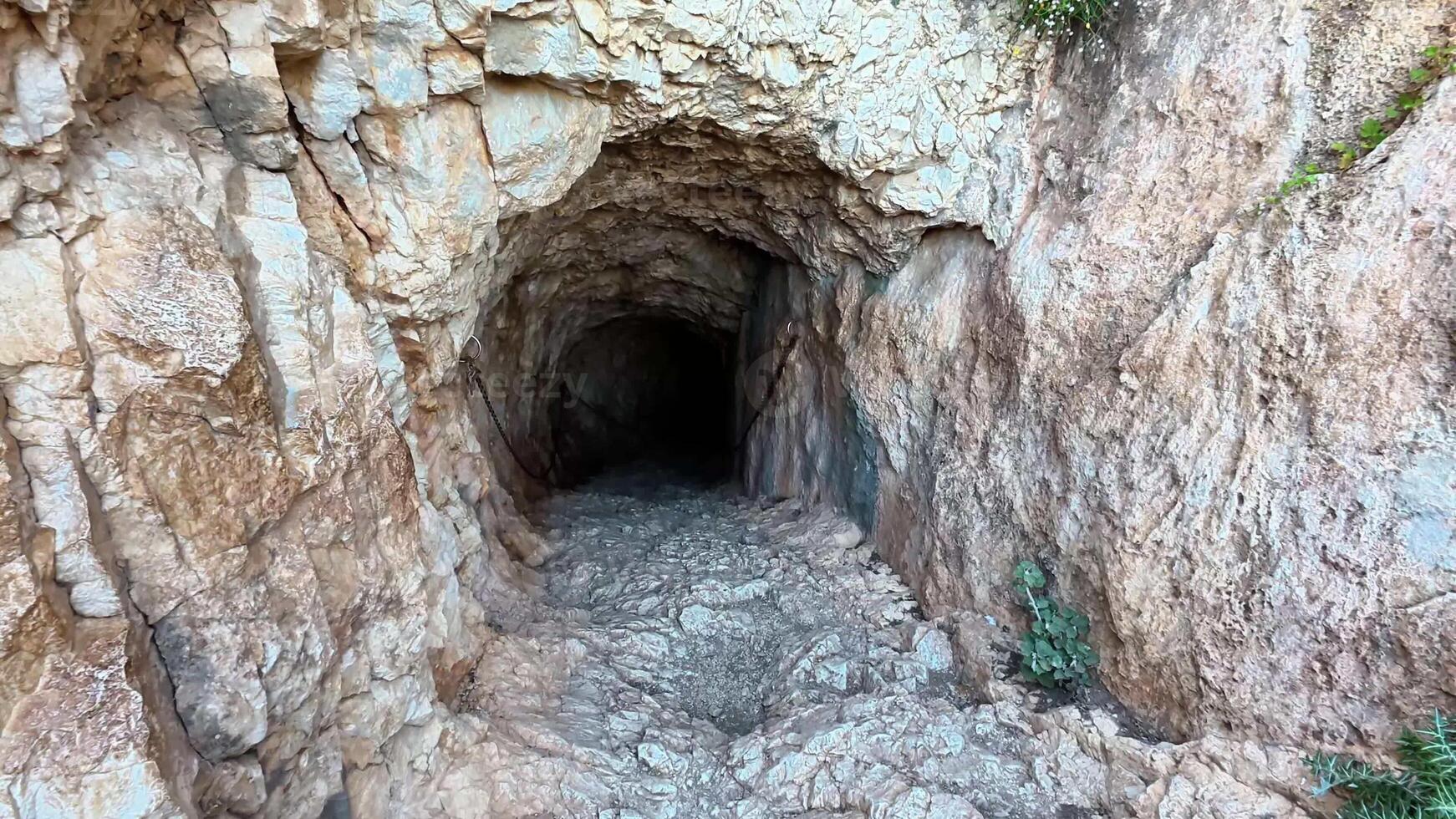 Venture into a mysterious tunnel with rocky walls leading to an intriguing dark passage waiting to be explored photo