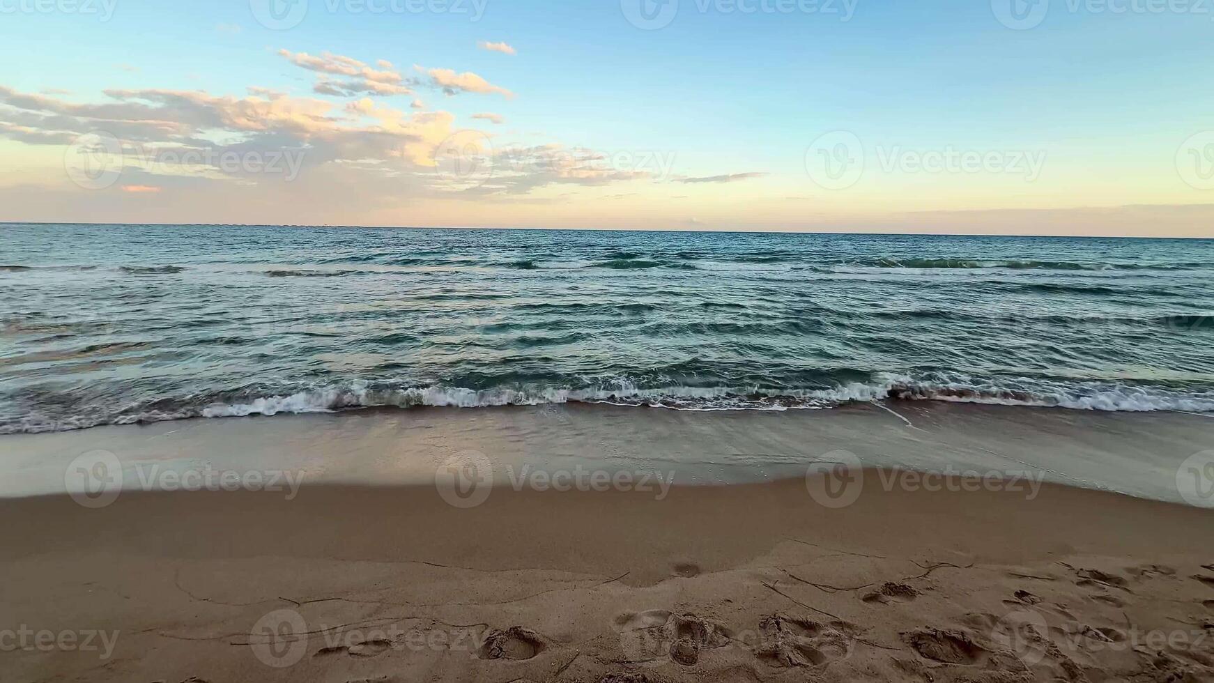 A breathtaking view of a beautiful sunset casting vibrant colors over calm ocean waves lapping softly at a sandy beach photo
