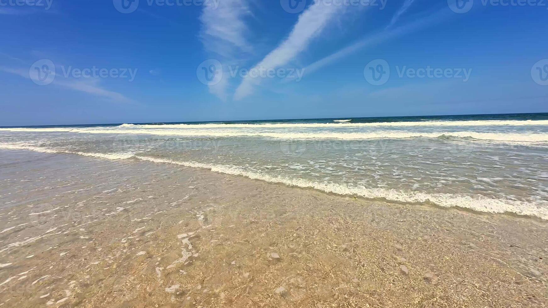 A serene beach scene, showcasing the clear, inviting waters beneath a bright, limitless blue sky overhead photo