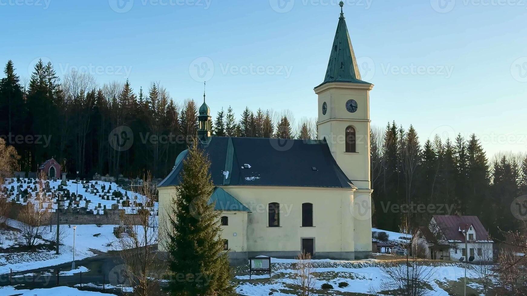 A picturesque church nestled in a snowy winter landscape with trees, capturing the serenity of the season photo