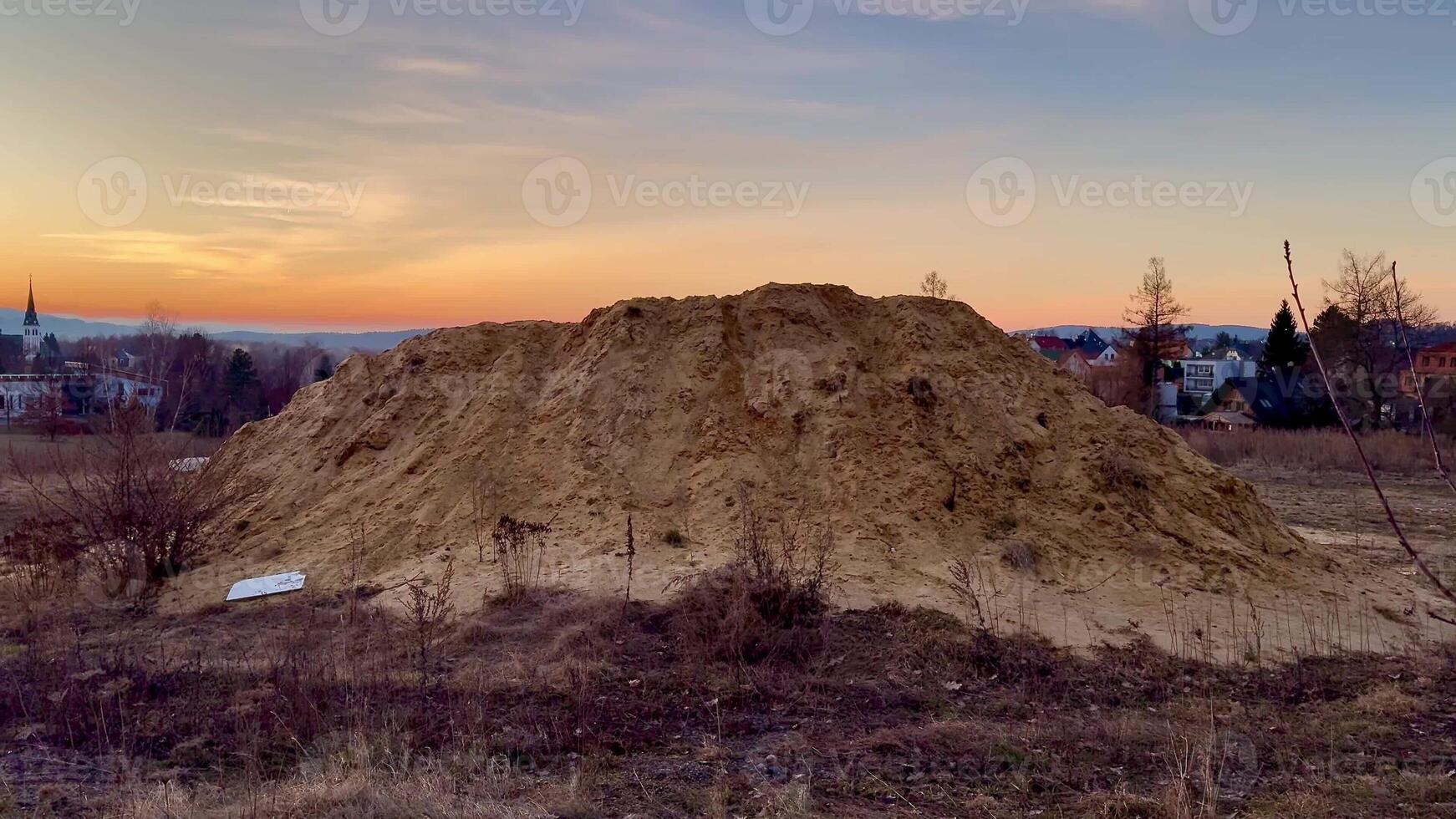 A vast and large mound of soft sand with a stunning vibrant sunset and fluffy clouds in the background sky photo