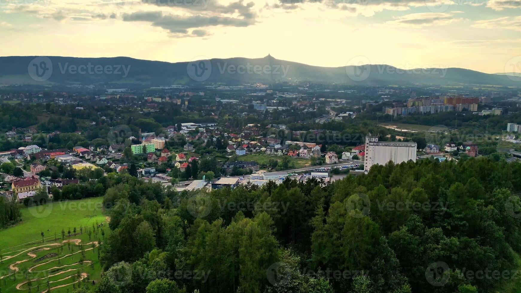 A stunning aerial perspective showcases lush green hills alongside serene mountains stretching beneath photo