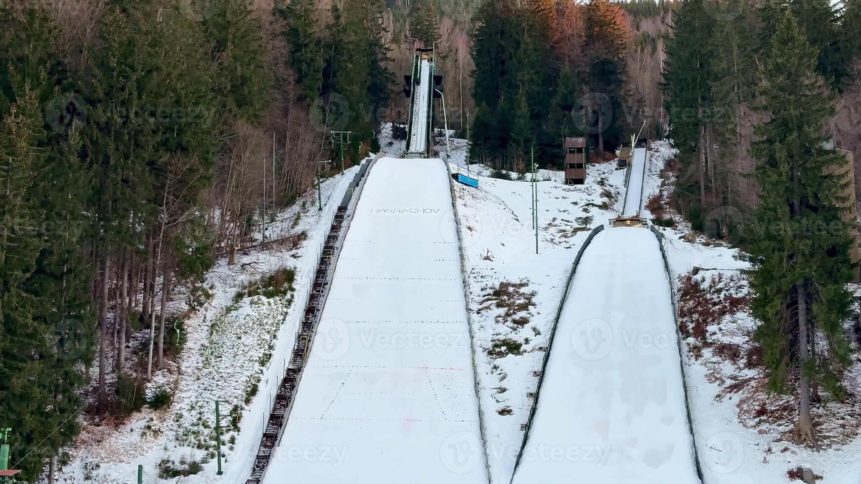 A picturesque winter landscape showcasing impressive ski jumping ramps that are nestled among the trees photo