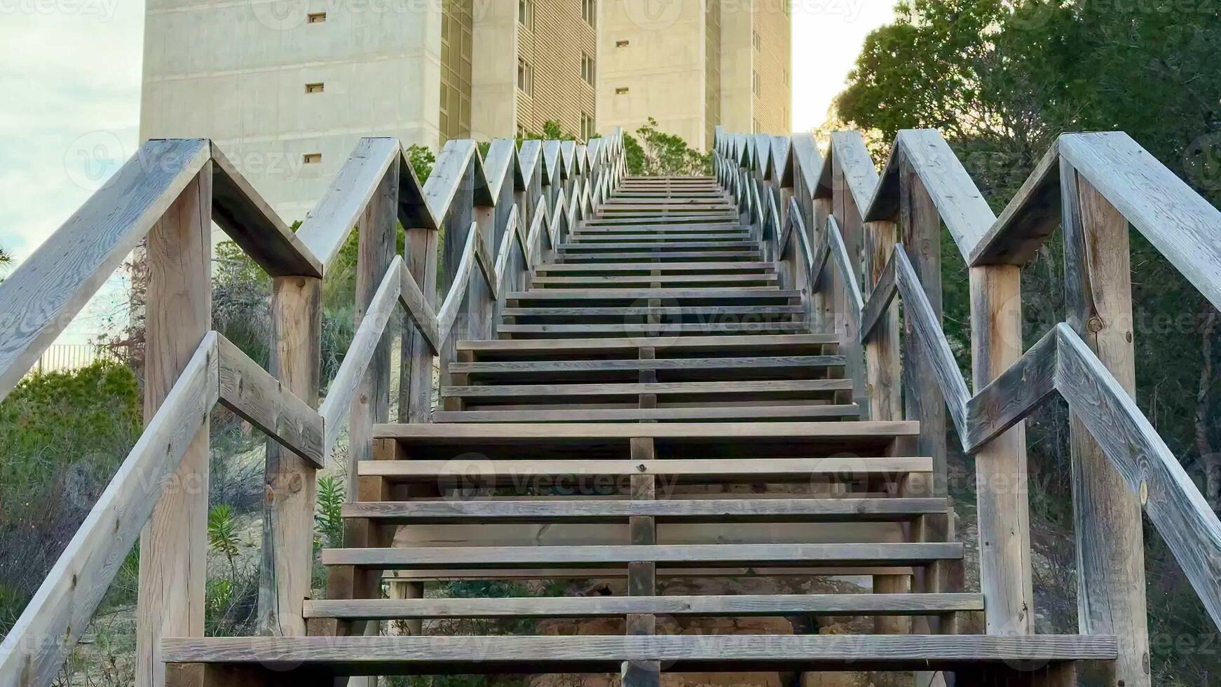 A wooden stairway leads to a modern concrete tower, surrounded by lush greenery that enhances the scenic view photo