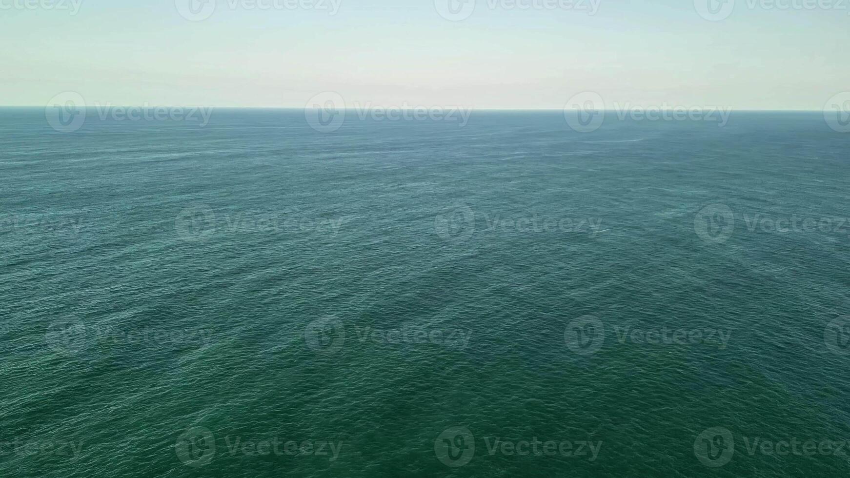 A stunning aerial photograph depicting a tranquil ocean landscape, sprinkled with ships beneath a clear blue sky photo