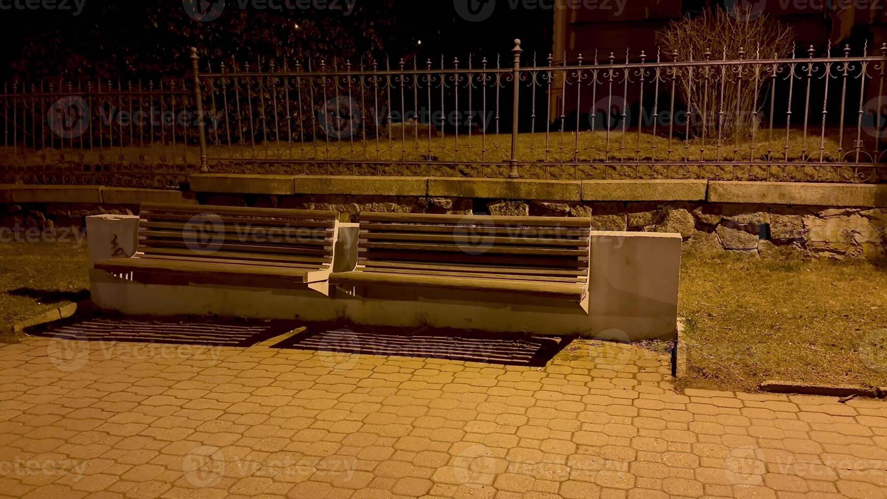 A solitary park bench, softly illuminated at night, beautifully highlights subtle urban tranquility and peace photo