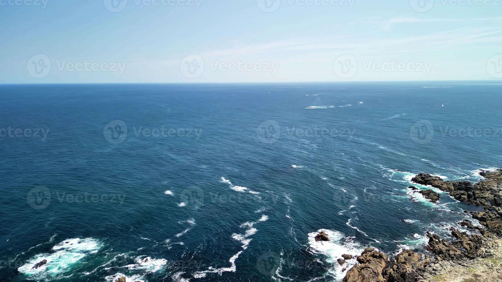 The breathtaking ocean view from a high cliff beautifully showcases the waves rolling in under blue skies photo