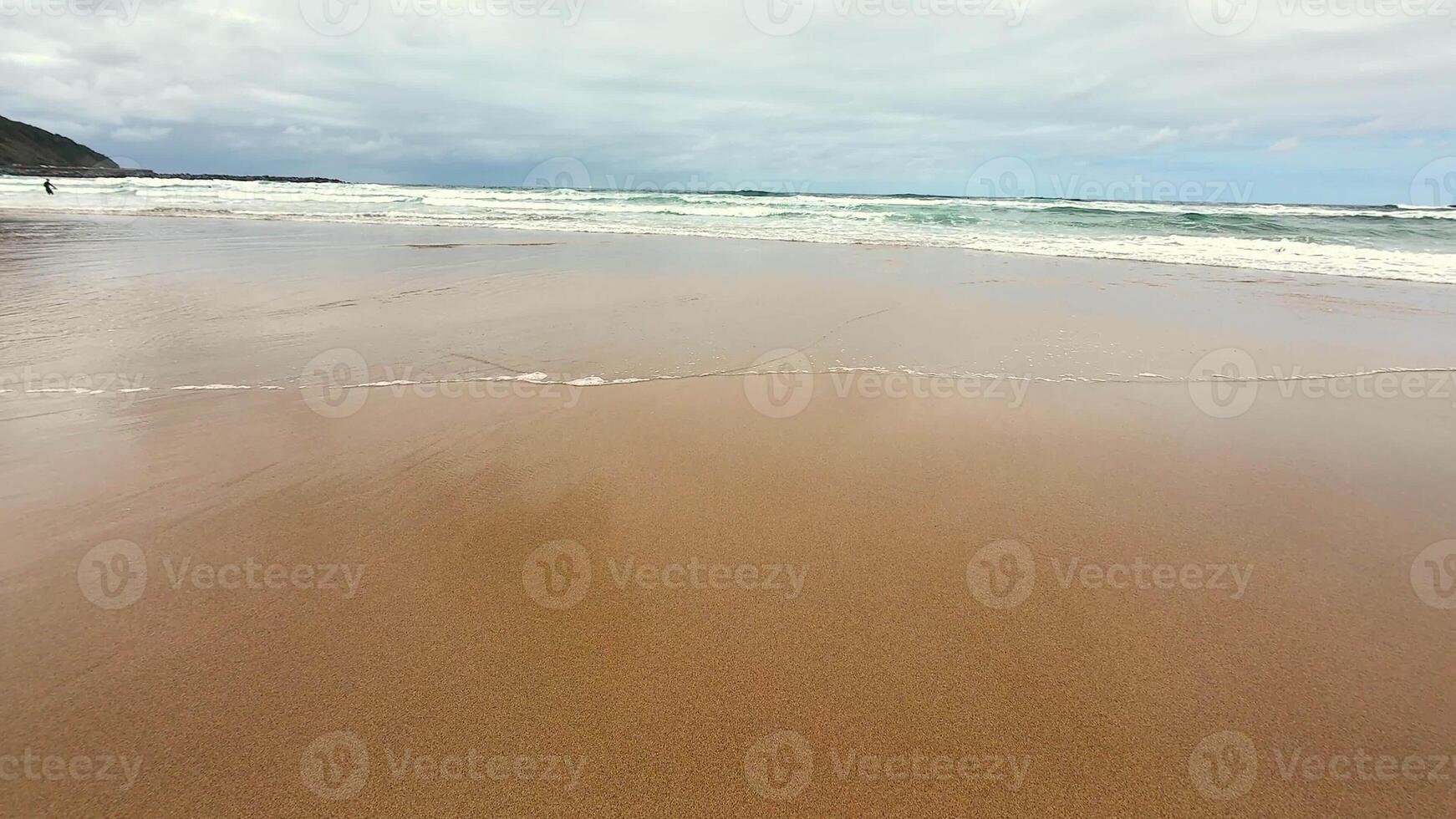Imagine a tranquil beach scene showcasing soft golden sand and gentle ocean waves rolling in beneath a cloudy sky photo