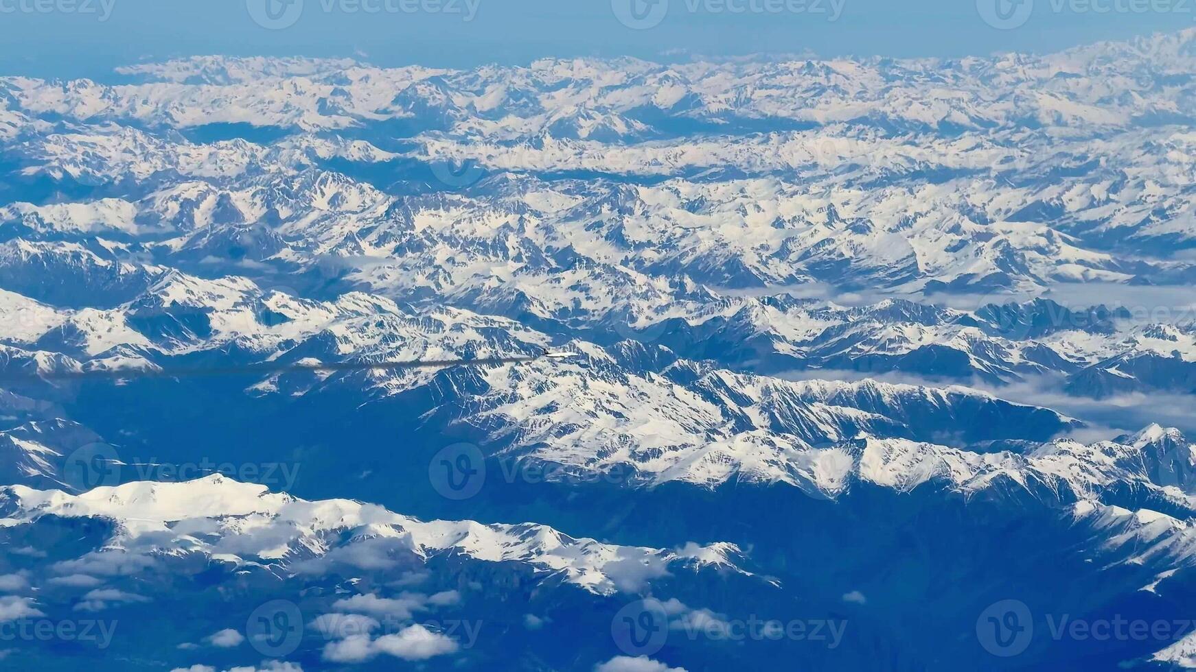 A breathtaking aerial view showcasing stunning, majestic, snowcapped mountain ranges beneath clear blue skies photo