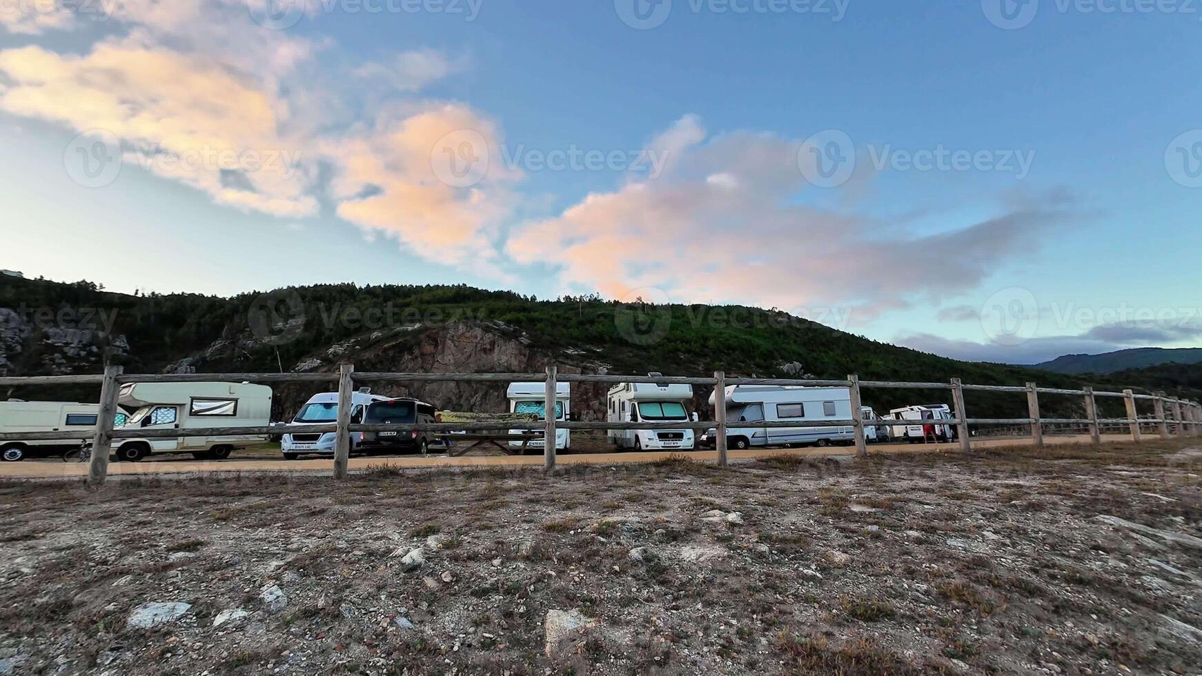 A beautiful and picturesque scene depicting RVs parked gracefully beside a scenic hillside under a bright, vibrant sky photo