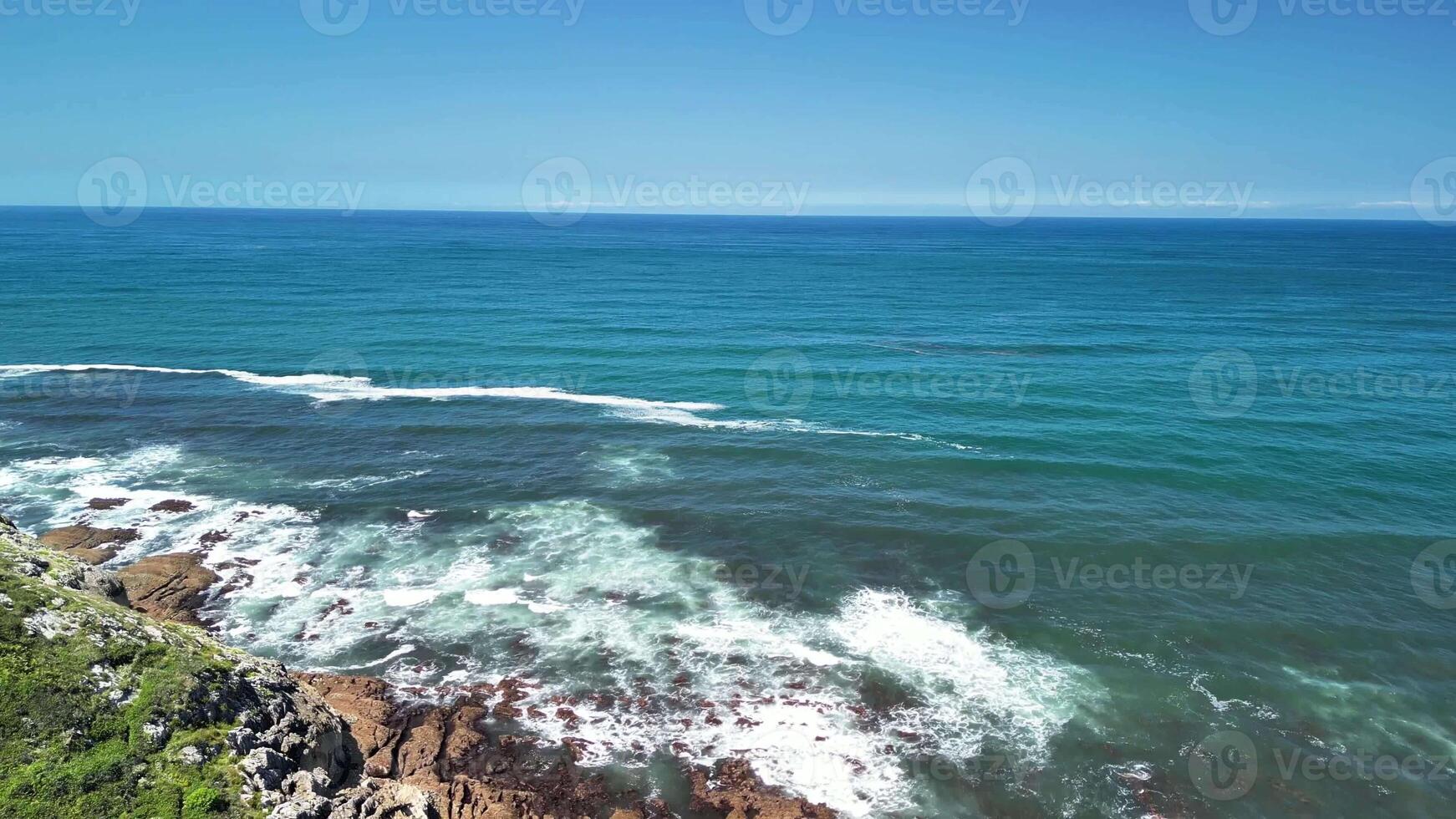 Experience the breathtaking and mesmerizing view of ocean waves gently meeting the coastline under a clear blue sky photo