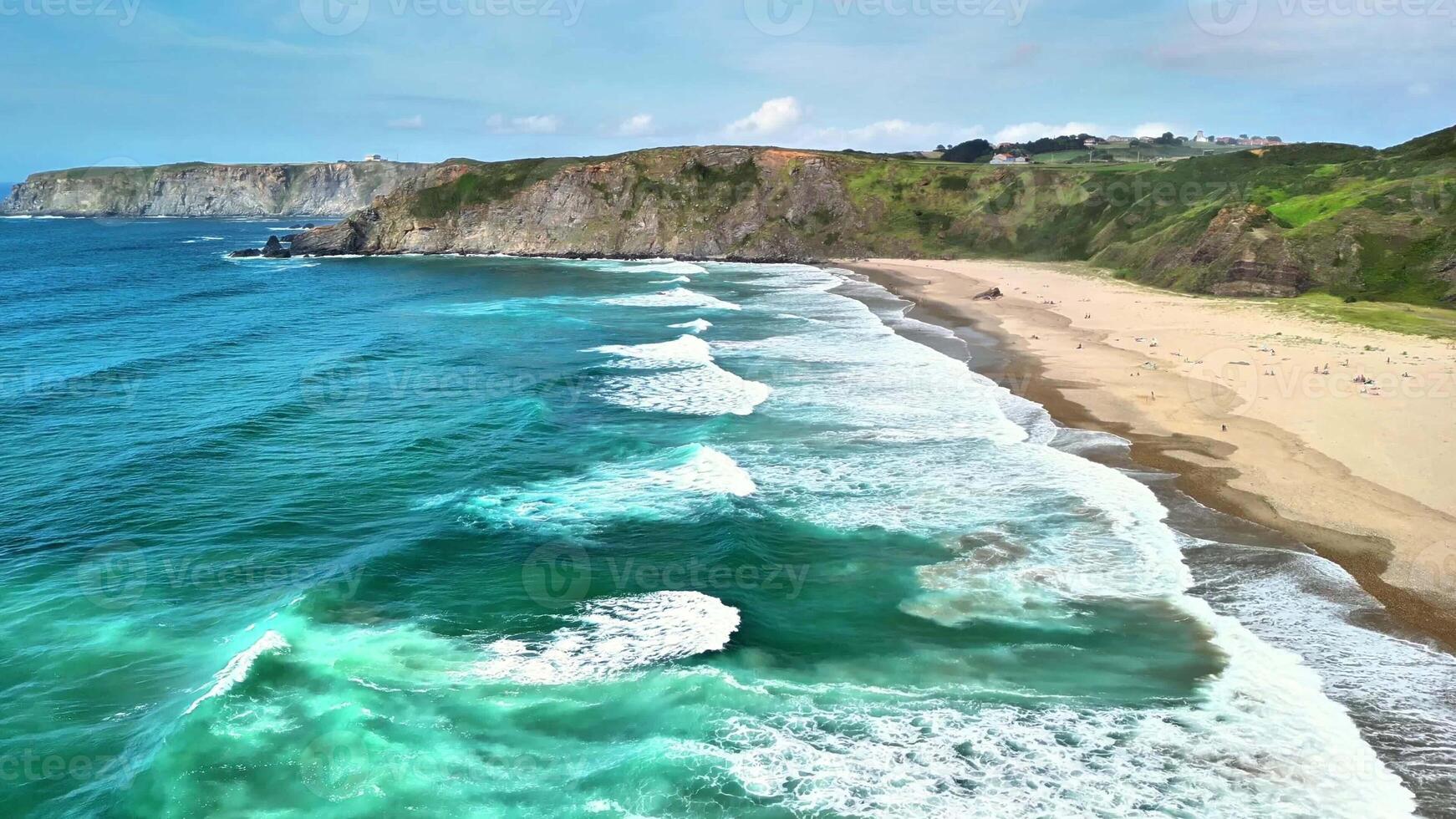 Aerial view showcasing the tranquil waves meeting a beautiful sandy beach against a scenic cliff backdrop. photo