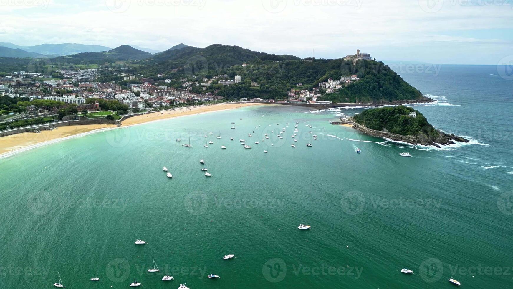 Aerial view of a picturesque beach, surrounded by lush hills, with boats bobbing in sparkling water photo