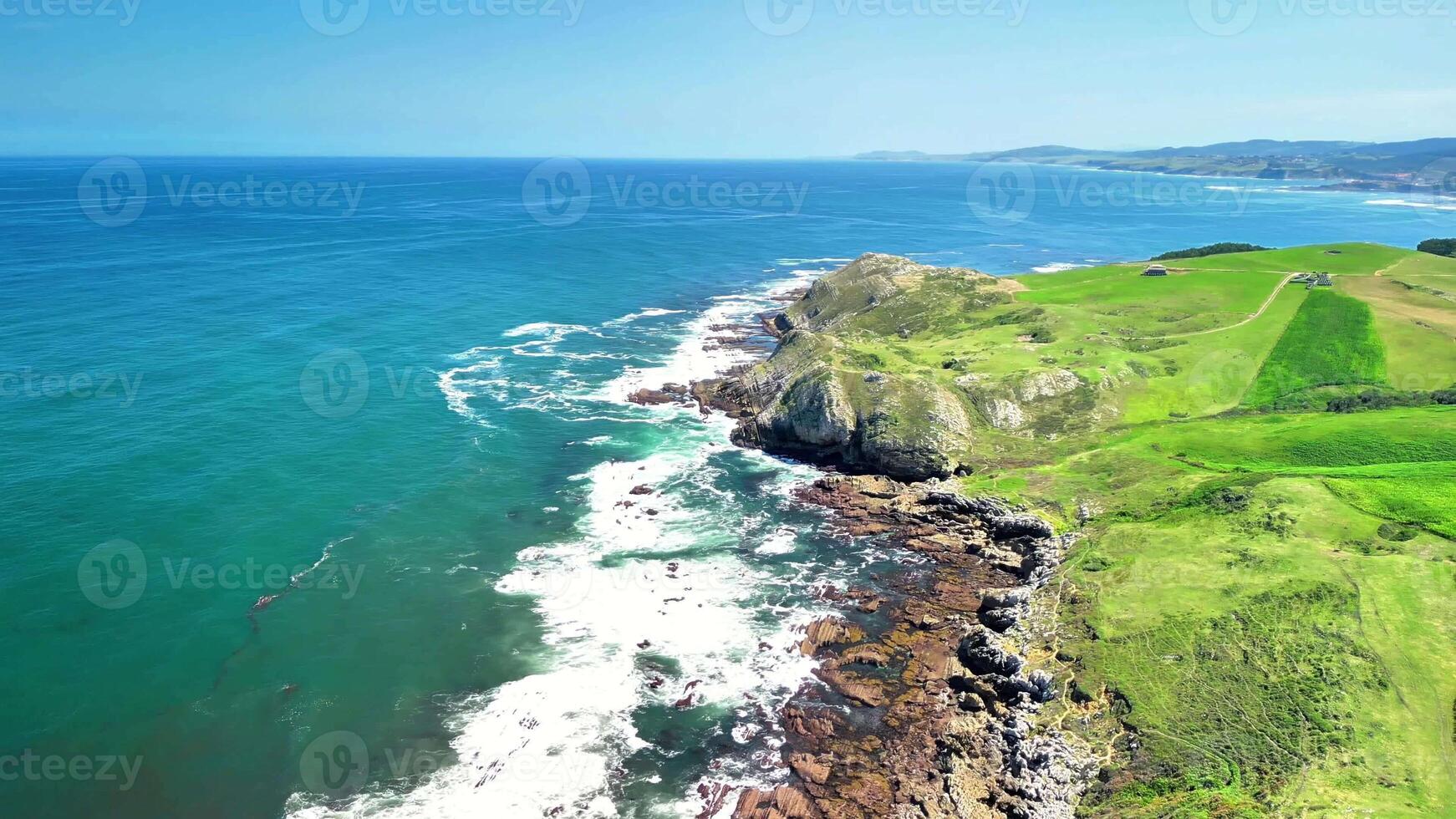 Experience a breathtaking aerial view showcasing a vibrant coastal landscape with powerful waves crashing against rocks photo